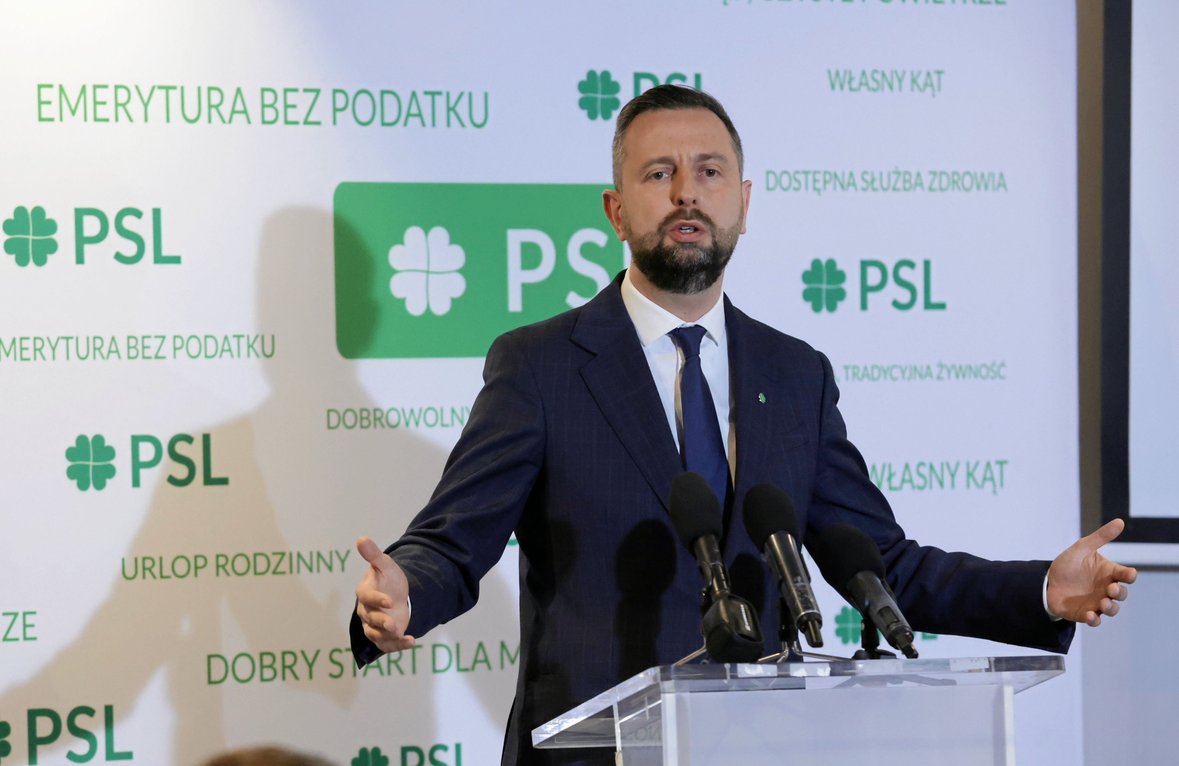 Szef PSL Władysław-Kosiniak Kamysz podczas konferencji prasowej rozkłada ręce na tle loga swojej partii