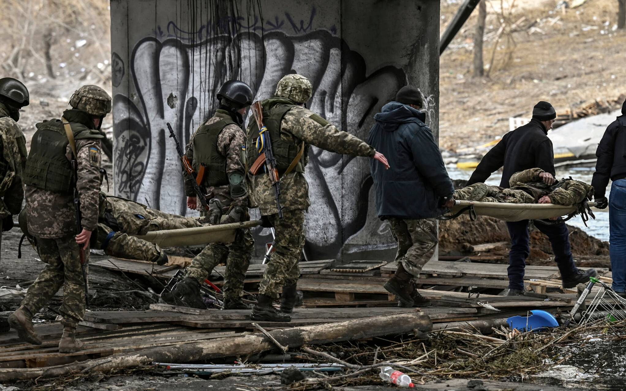 EDITORS NOTE: Graphic content / Ukranian servicemen carry the body of comrades on stretchers in the city of Irpin, northwest of Kyiv, on March 13, 2022. - Russian forces advance ever closer to the capital from the north, west and northeast. Russian strikes also destroy an airport in the town of Vasylkiv, south of Kyiv. A US journalist was shot dead and another wounded in Irpin, a frontline northwest suburb of Kyiv, medics and witnesses told AFP. (Photo by Aris Messinis / AFP)