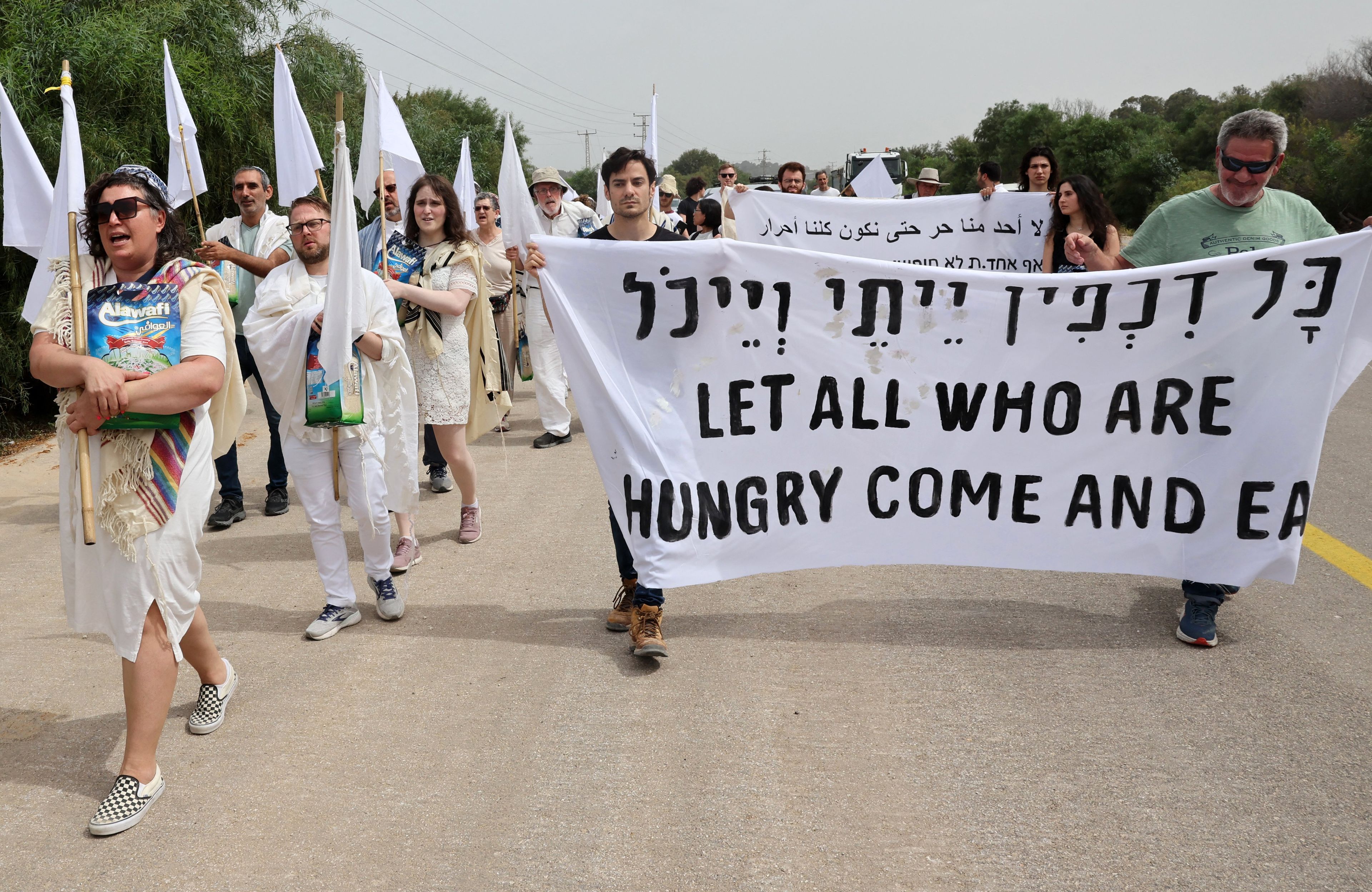 ubrani na biało protestujący niosą napis "let all who are hungry come and eat"
