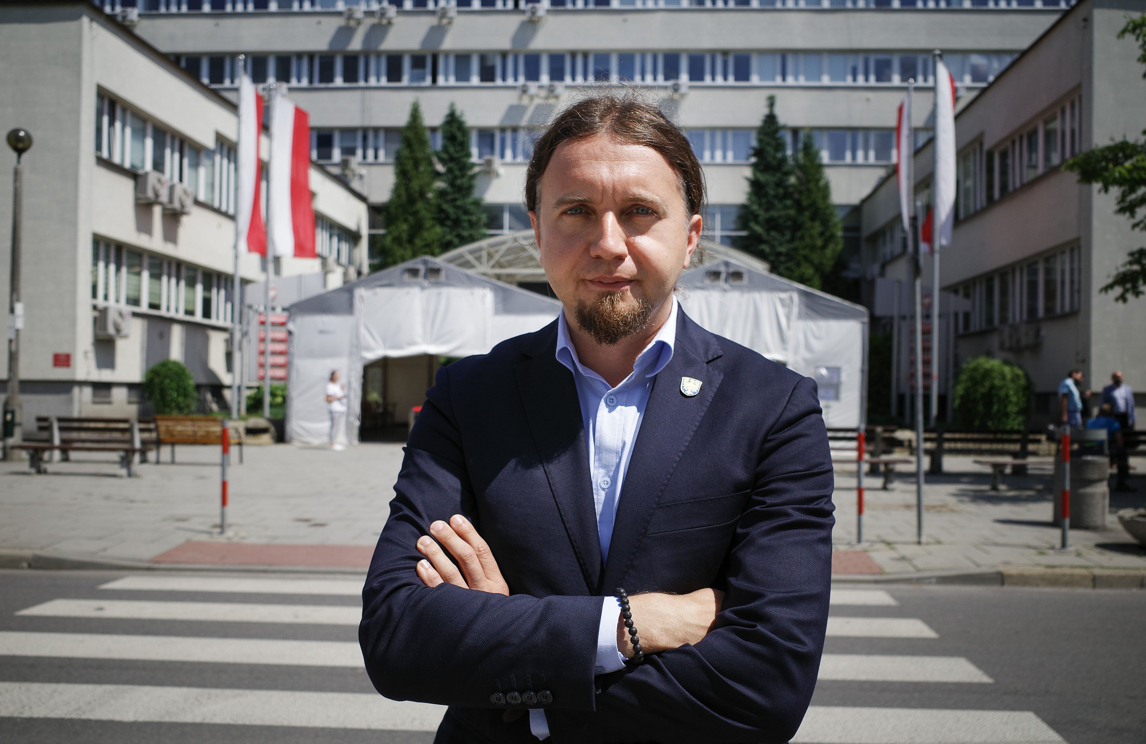 Europoseł Łukasz Kohut pozuje do zdjęcia z założonymi rękami