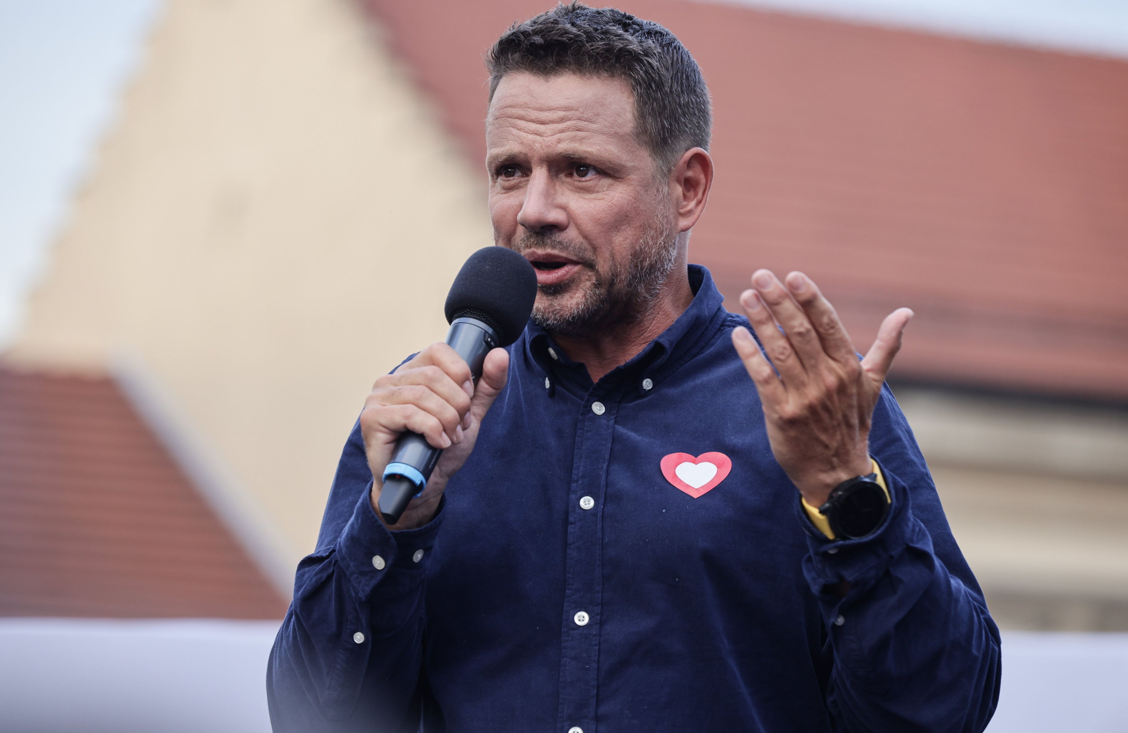Mężczyzna z mikrofonem w granatowej koszuli