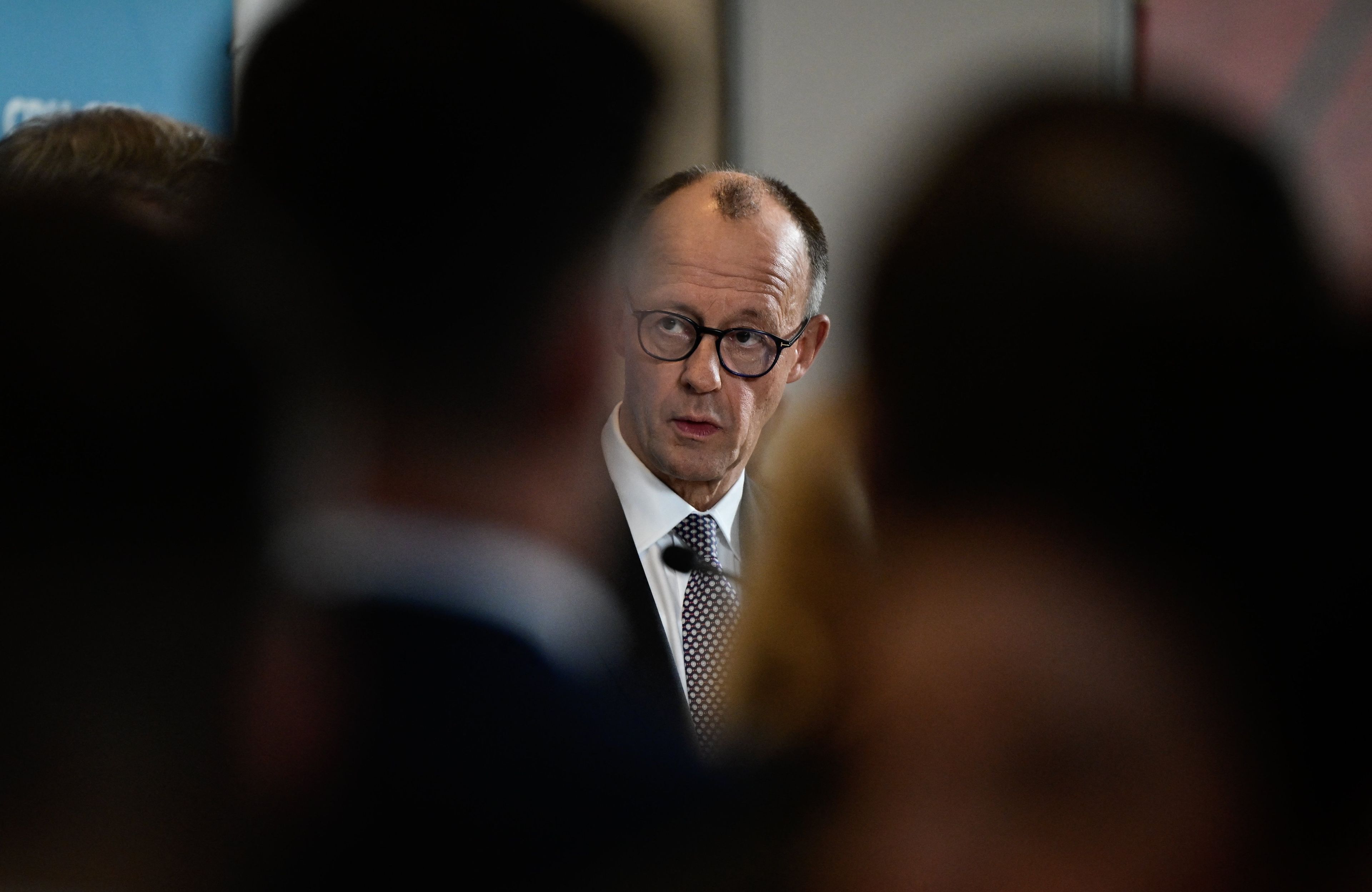 Twarz męzczyzny wyłania się zza sylwetek ludzi