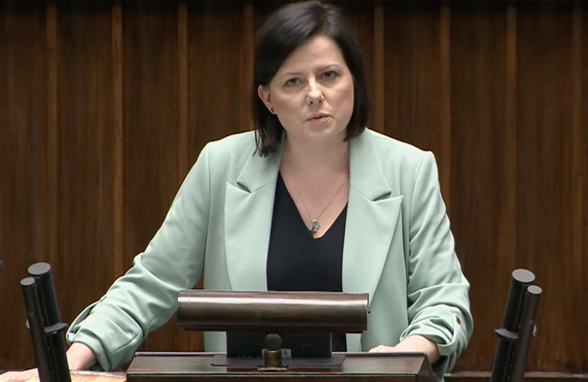 Kaja Godek w miętowym żakiecie przemawia z sejmowej mównicy