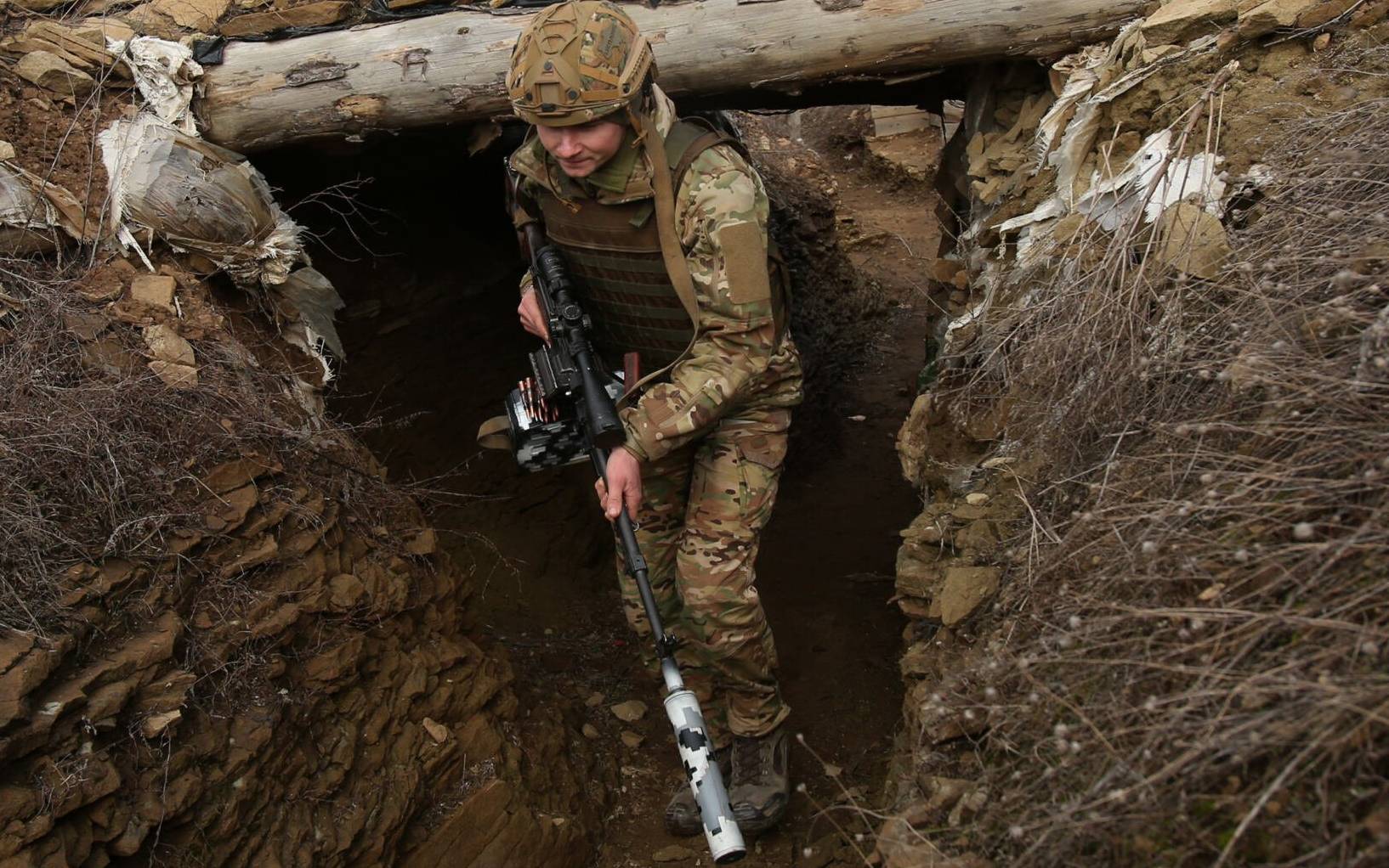 A Ukrainian serviceman walks along a trench at a position on the front line with Russia-backed separatists near the settlement of Troitske in the Lugansk region on February 22, 2022, a day after Russia recognised east Ukraine's separatist republics and ordered the Russian army to send troops there as "peacekeepers". - The recognition of Donetsk and Lugansk rebel republics effectively buries the fragile peace process regulating the conflict in eastern Ukraine, known as the Minsk accords. Russian President recognised the rebels despite the West repeatedly warning him not to and threatening Moscow with a massive sanctions response. (Photo by Anatolii STEPANOV / AFP)
