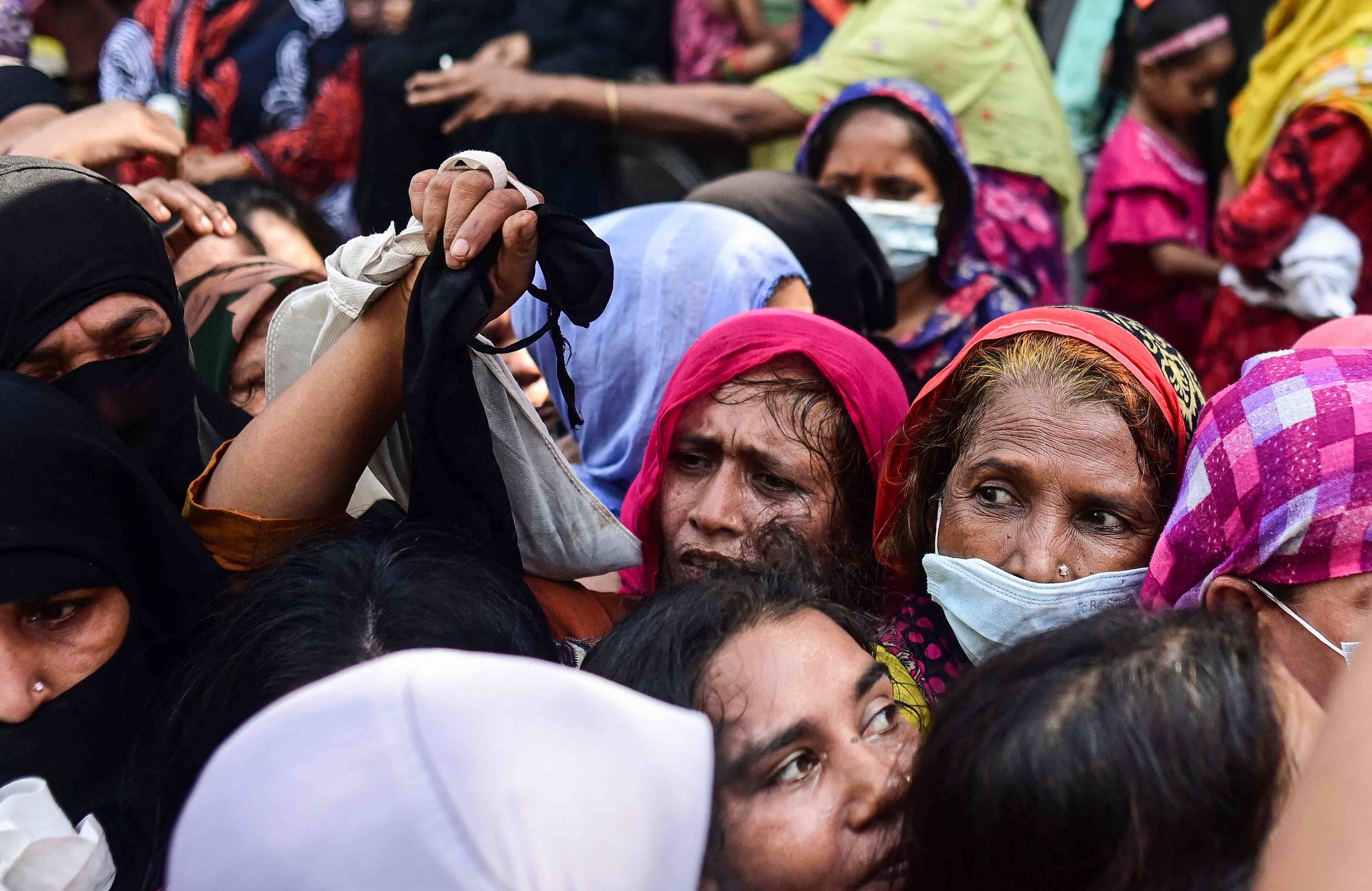 Kobiety w kolorowych chustachj na głowach tłoczą się w kolejce po żywność. Bangladesz