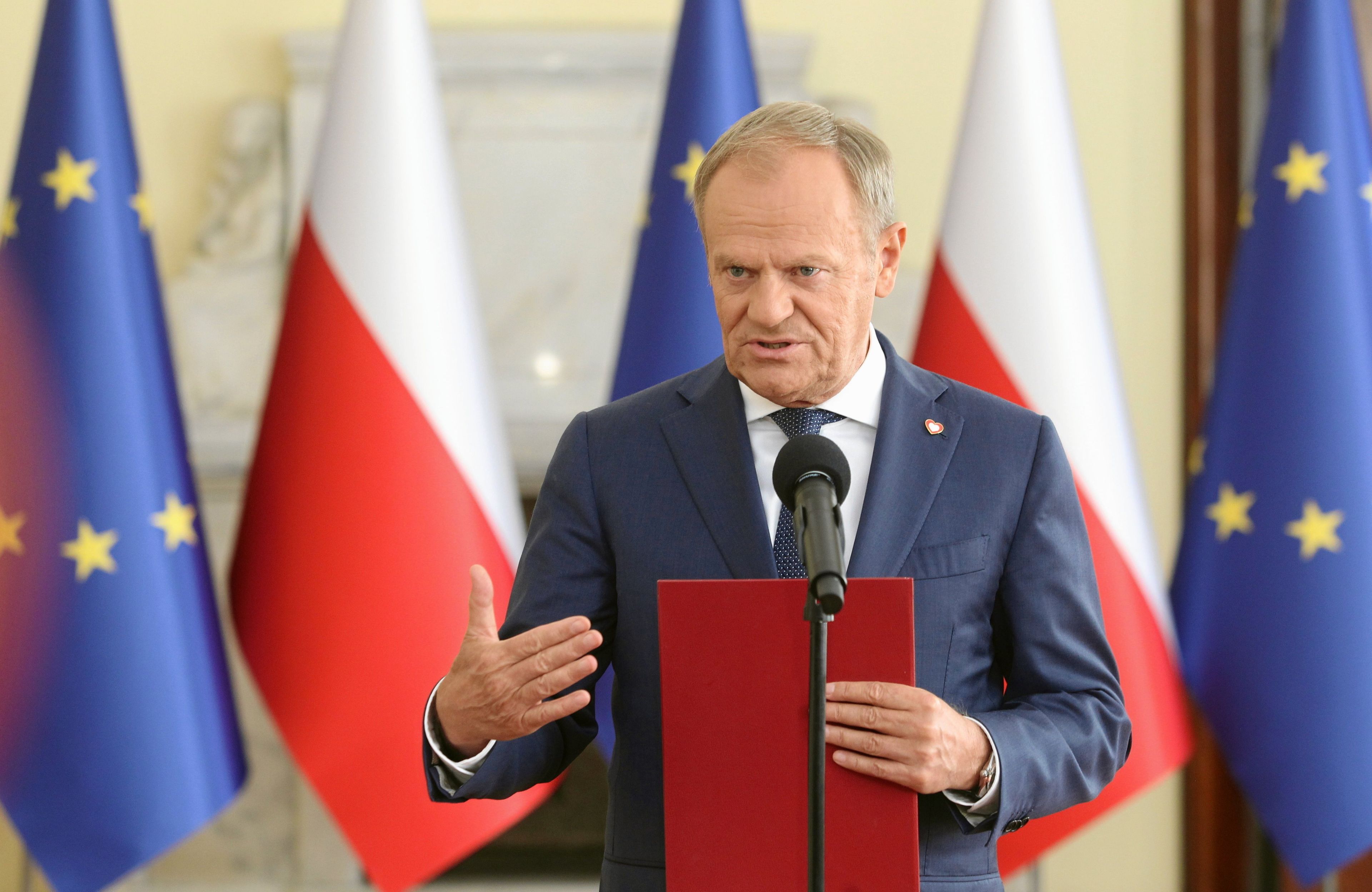 Premier Donald Tusk przemawia podczas konferencji prasowej na tle flag polskich i UE