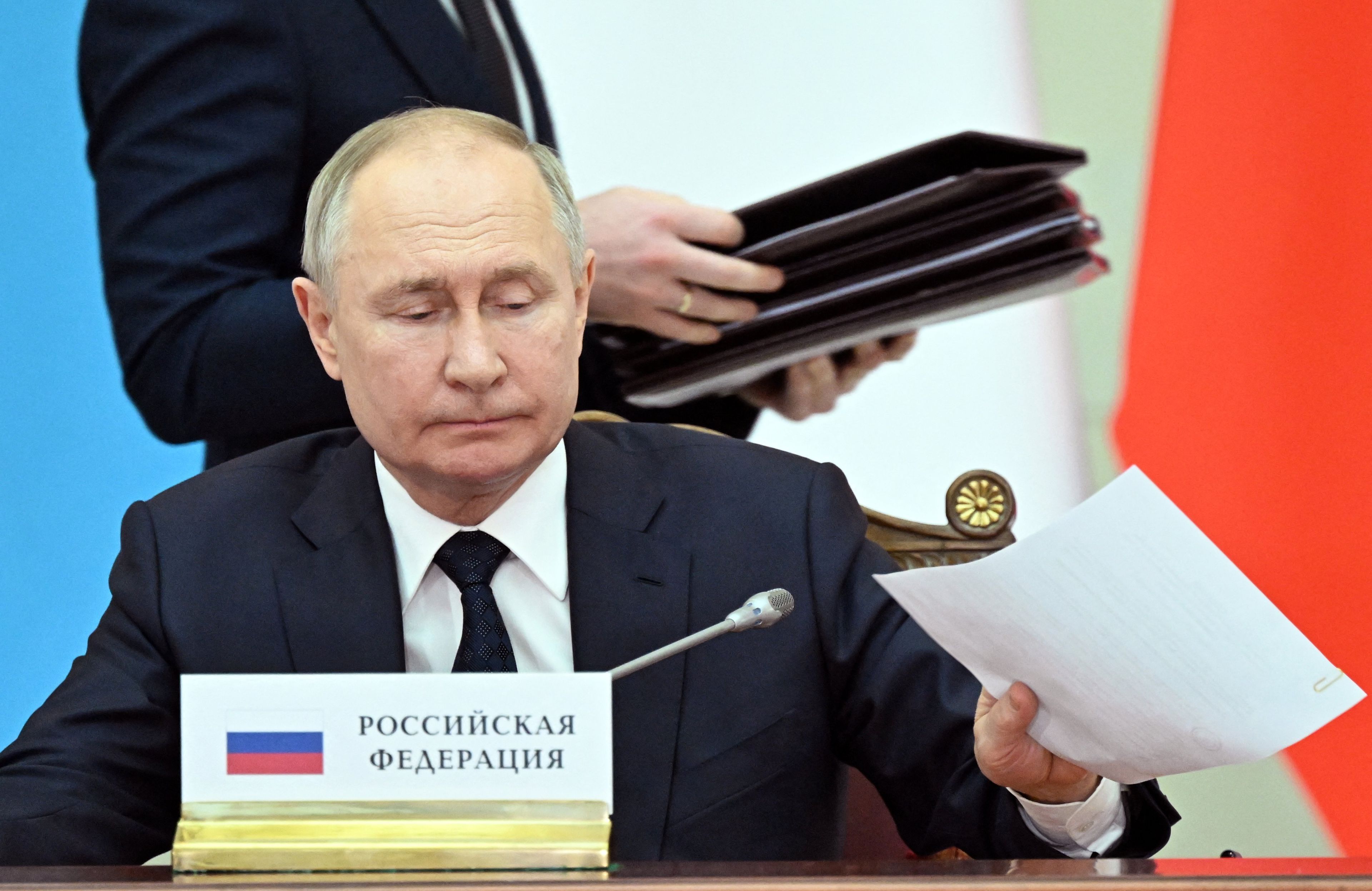 Władymir Putin, w tle człowiek z teczką