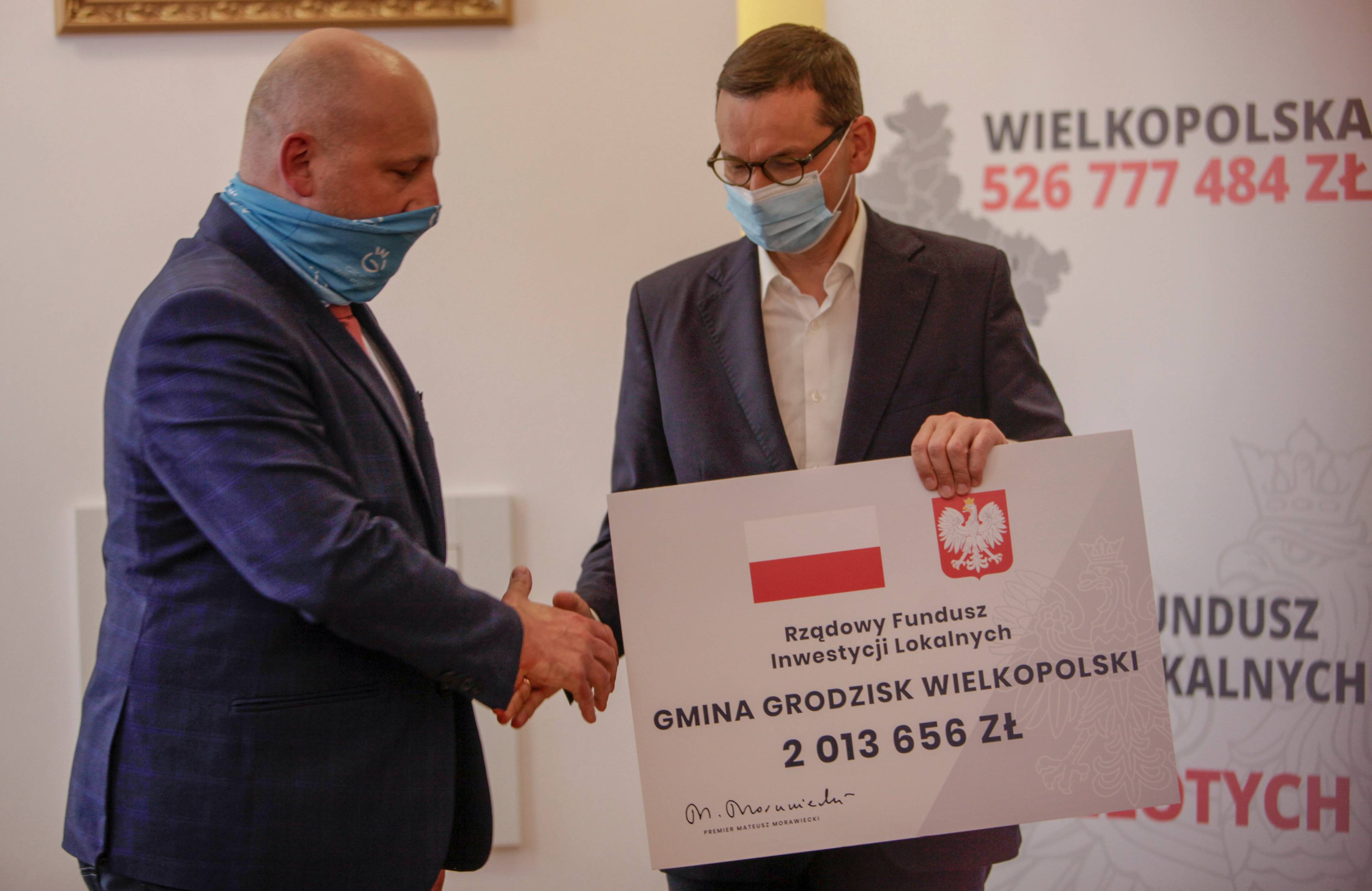 Premoier Morawiecki wręcza wielka planszę - "czek" symbolizujący dotacje z funduszu inwestycji lokalnych