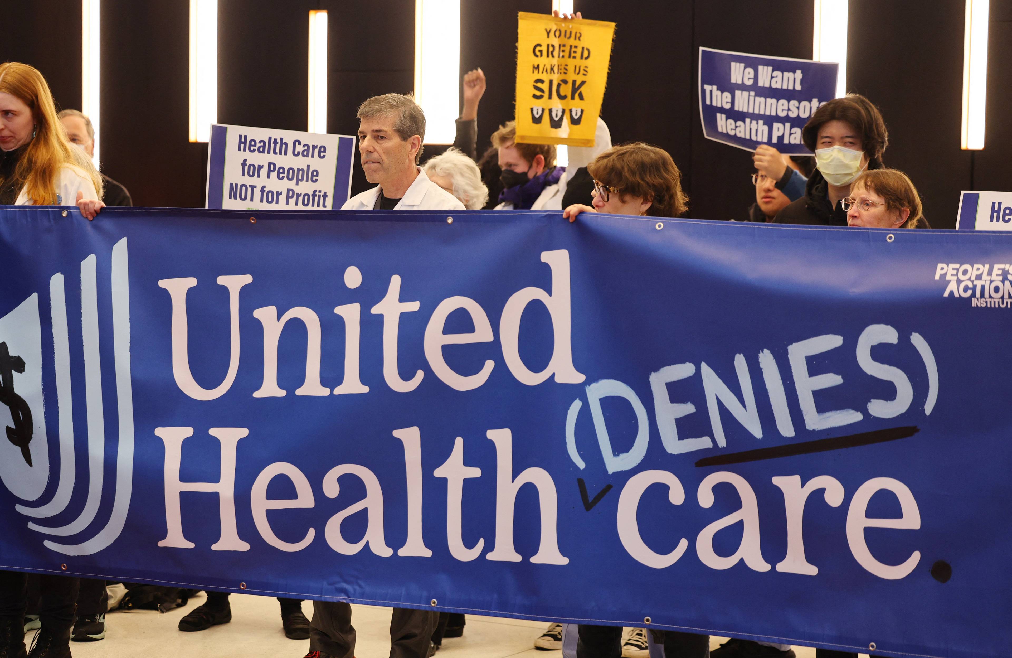Protestujący trzymają transparent z napisem United (denies) Health care