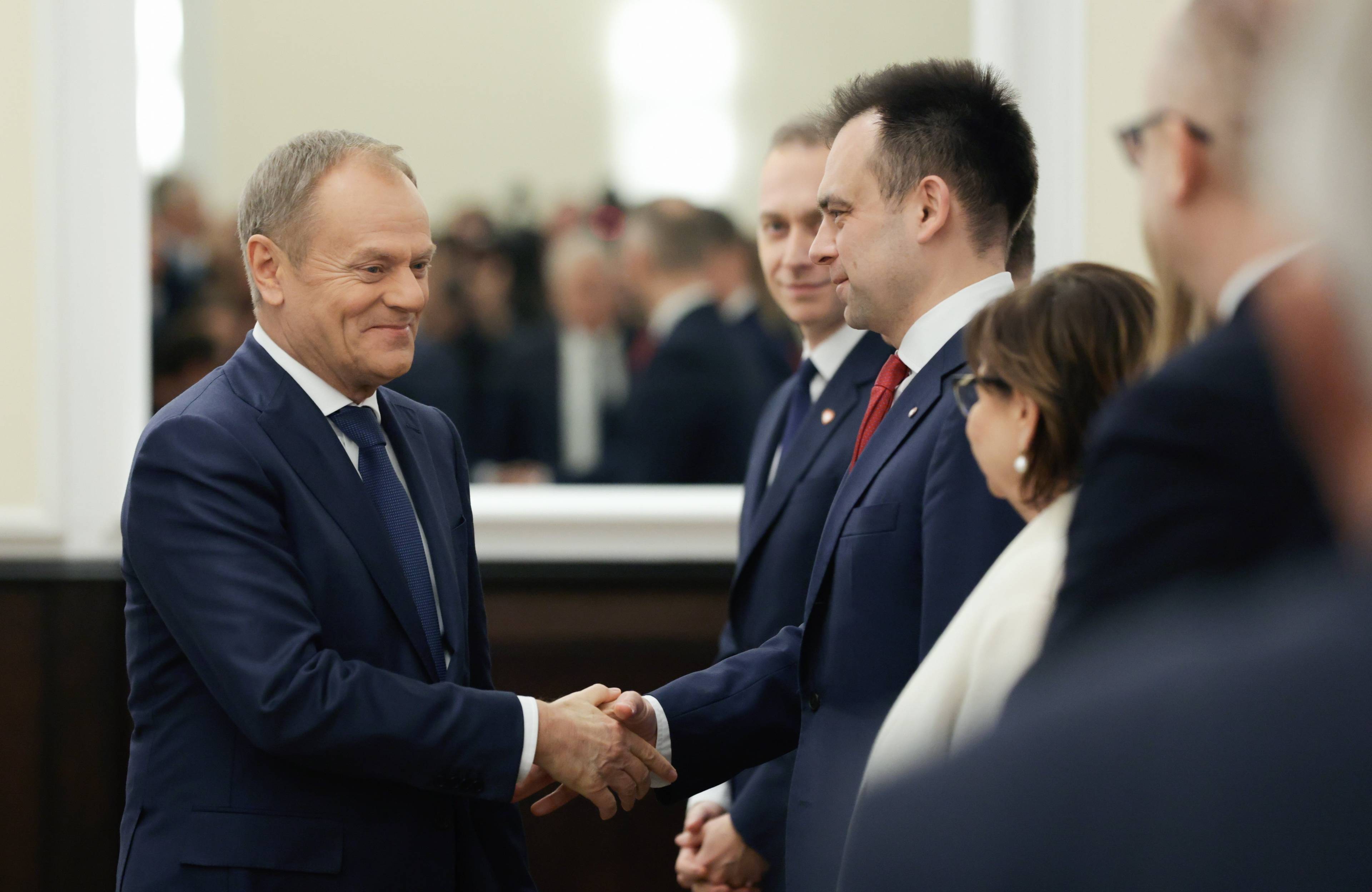 Premier Donald Tusk ściska dłoń ministra finansów Andrzeja Domańskiego