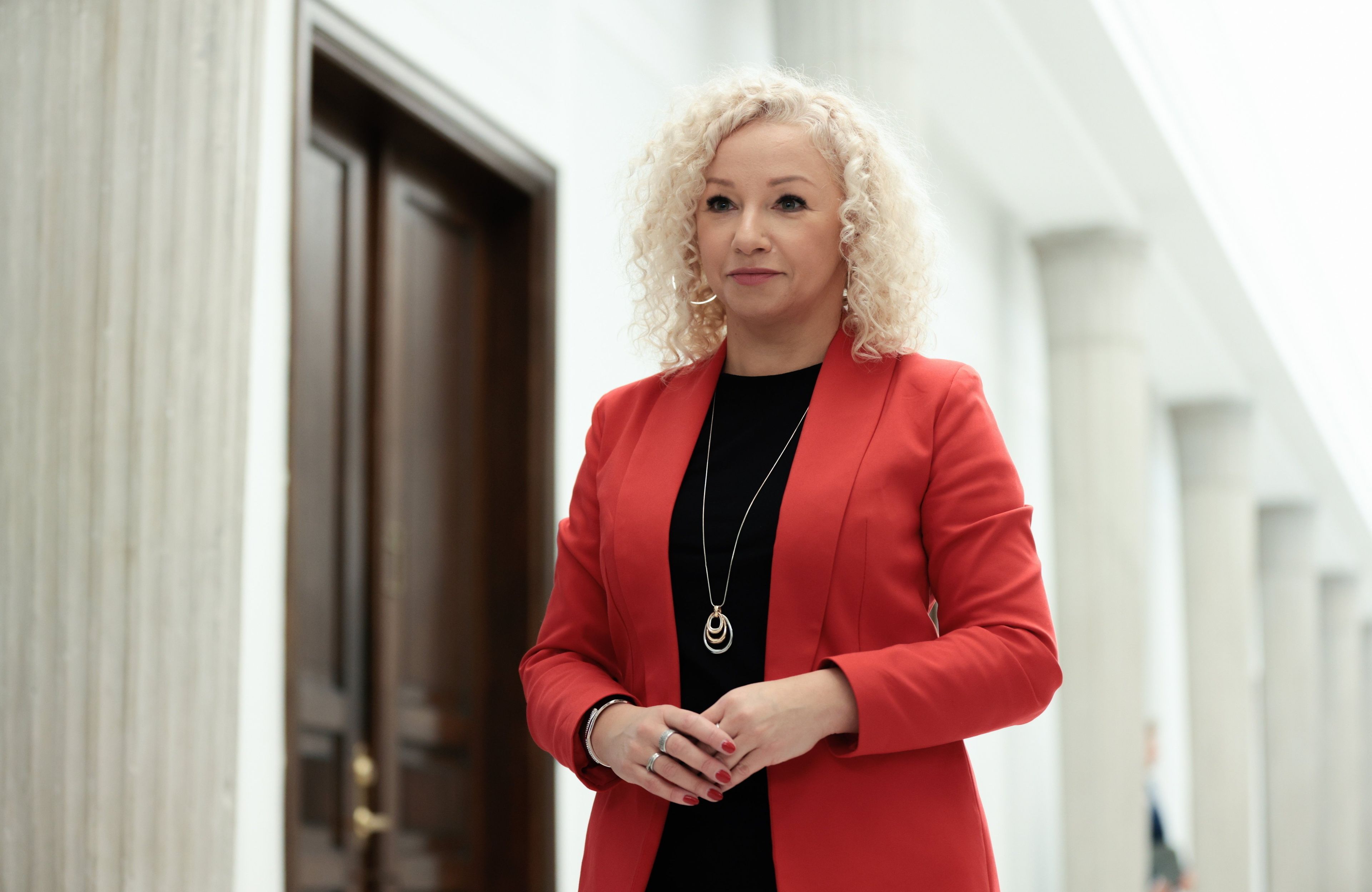 Kobieta w czerwonęj marynarce, długie blond włosy