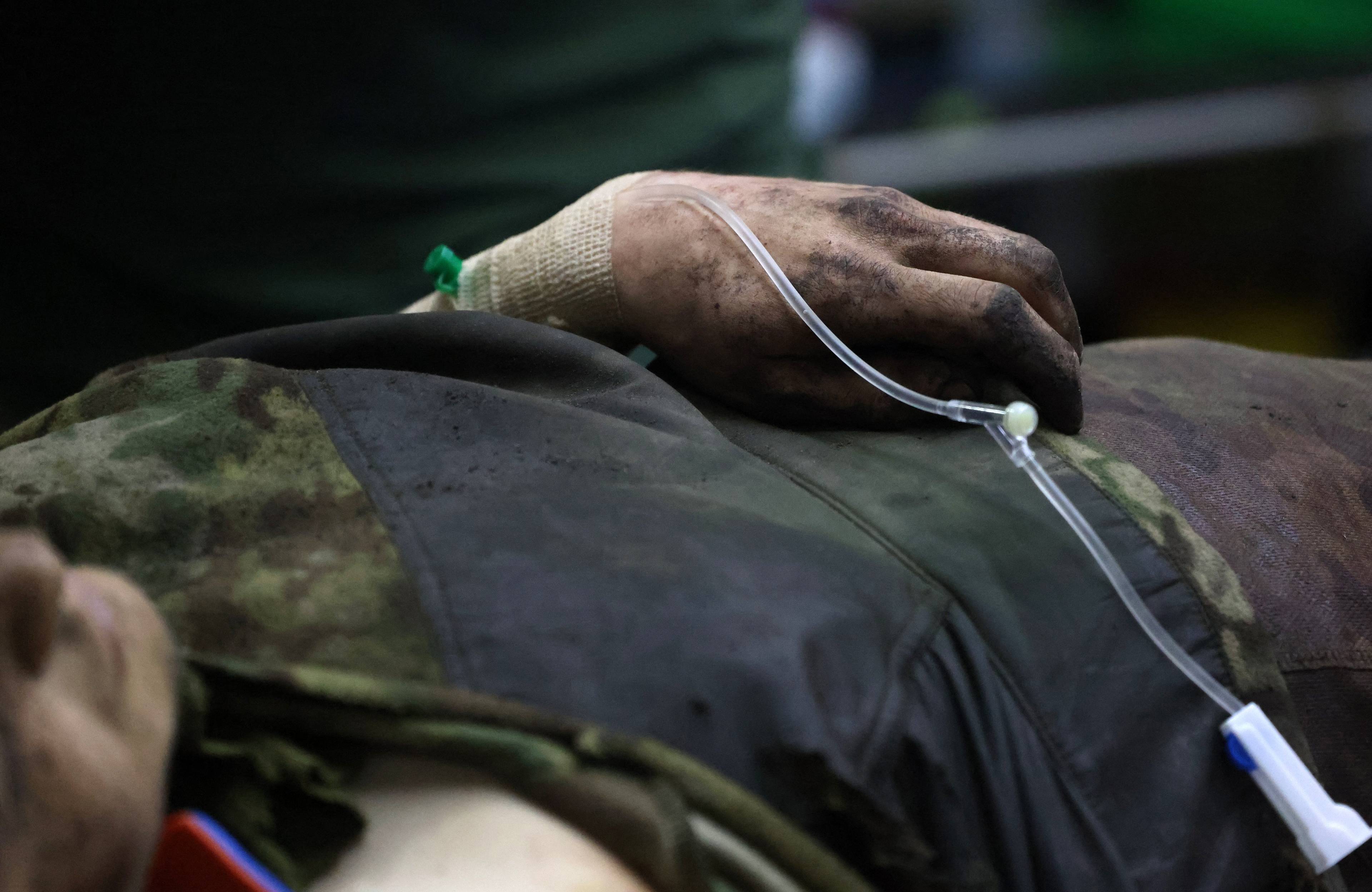 Na zdjęciu widać ludzki tułów i brudną rękę z króplówką. Odzież osoby też jest brudna, wiadać fragmenty kamuflażu