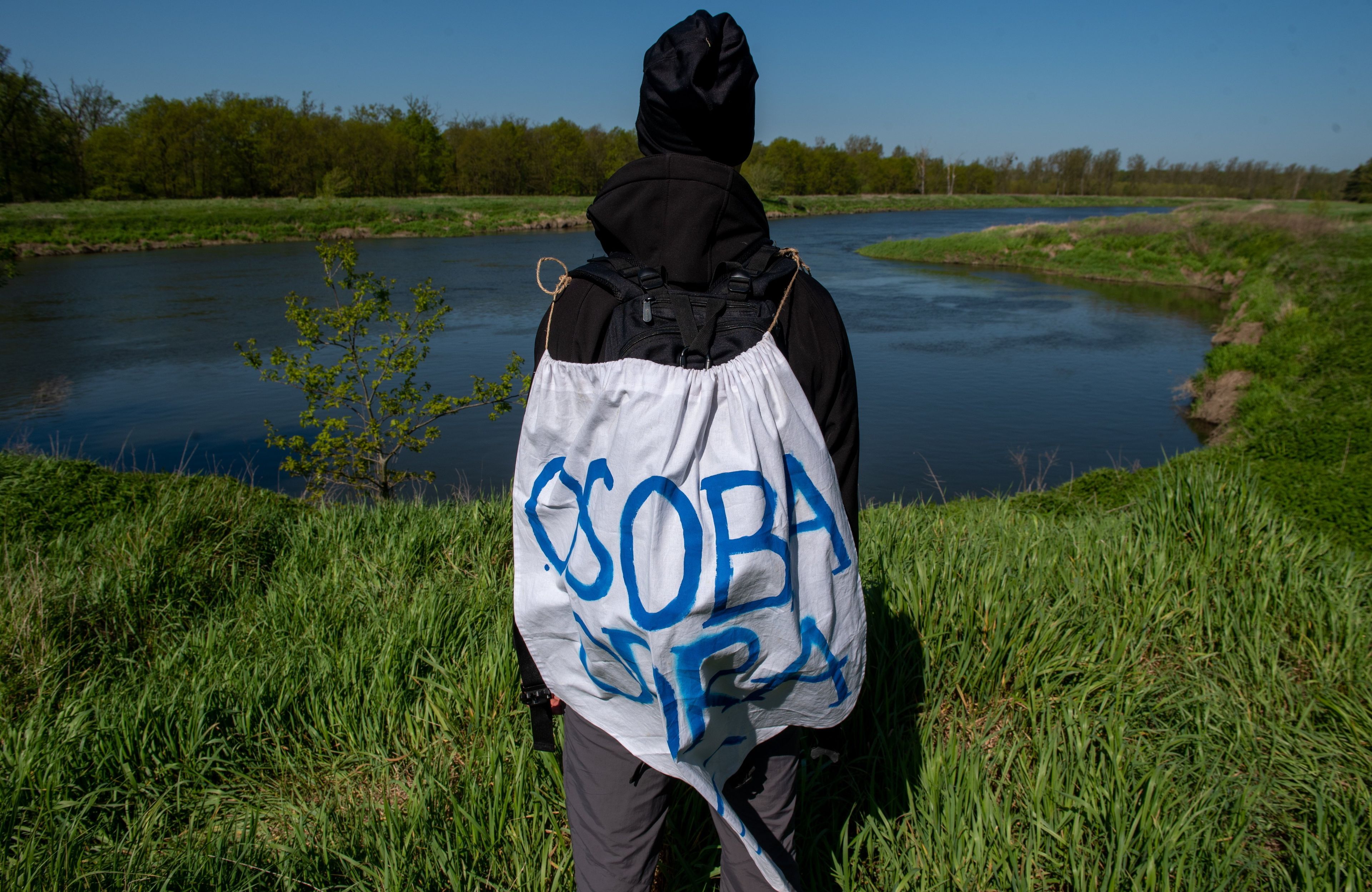 osoba stoi z płachtą na plecach, na której napisane jest "osoba odra", w tle widać rzekę