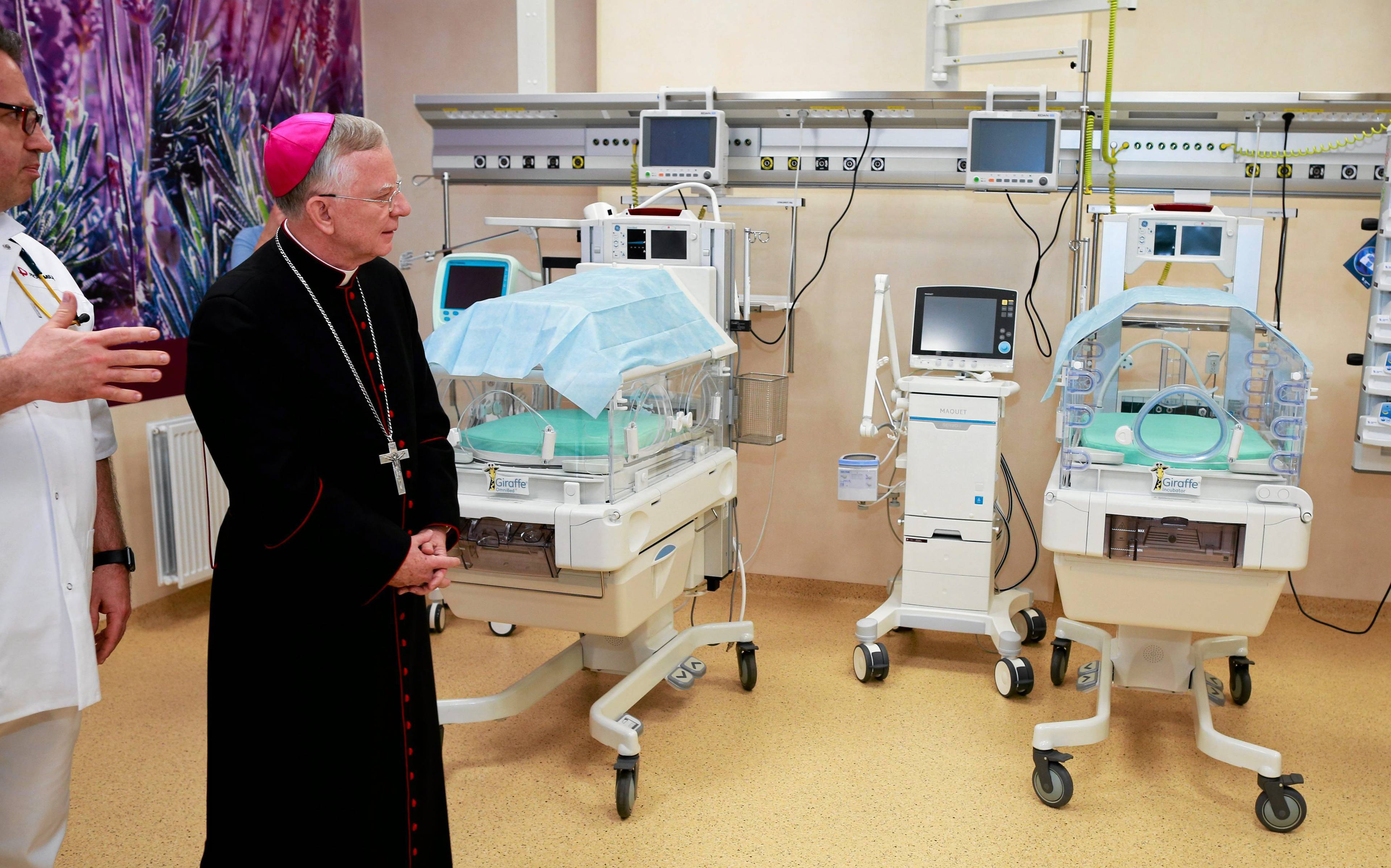 Biskup w sali szpitalnej z inkubatorami dla wcześniaków