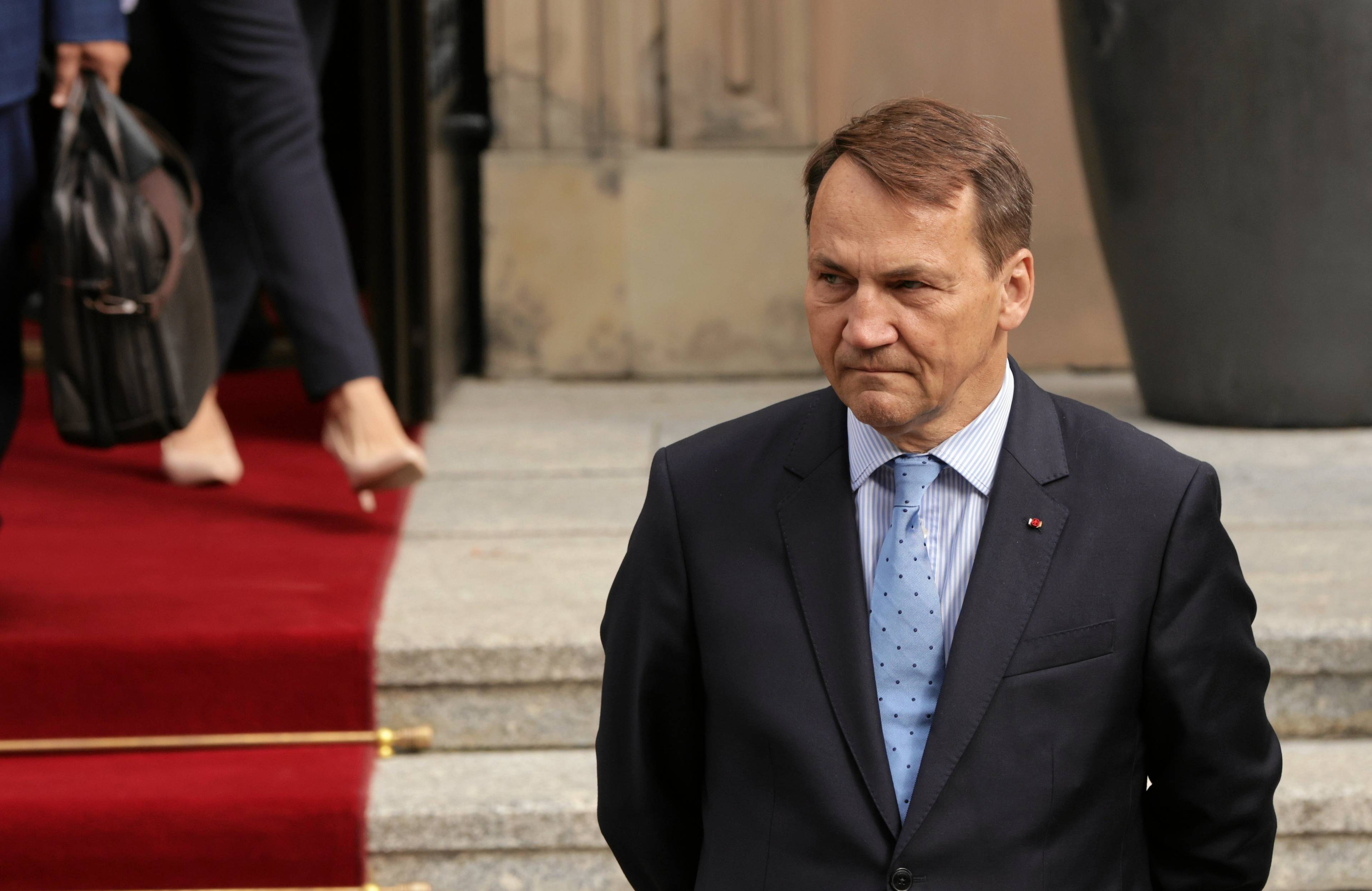 Minister Spraw Zagranicznych Radosłąw Sikorski w garniturze, w tle schody