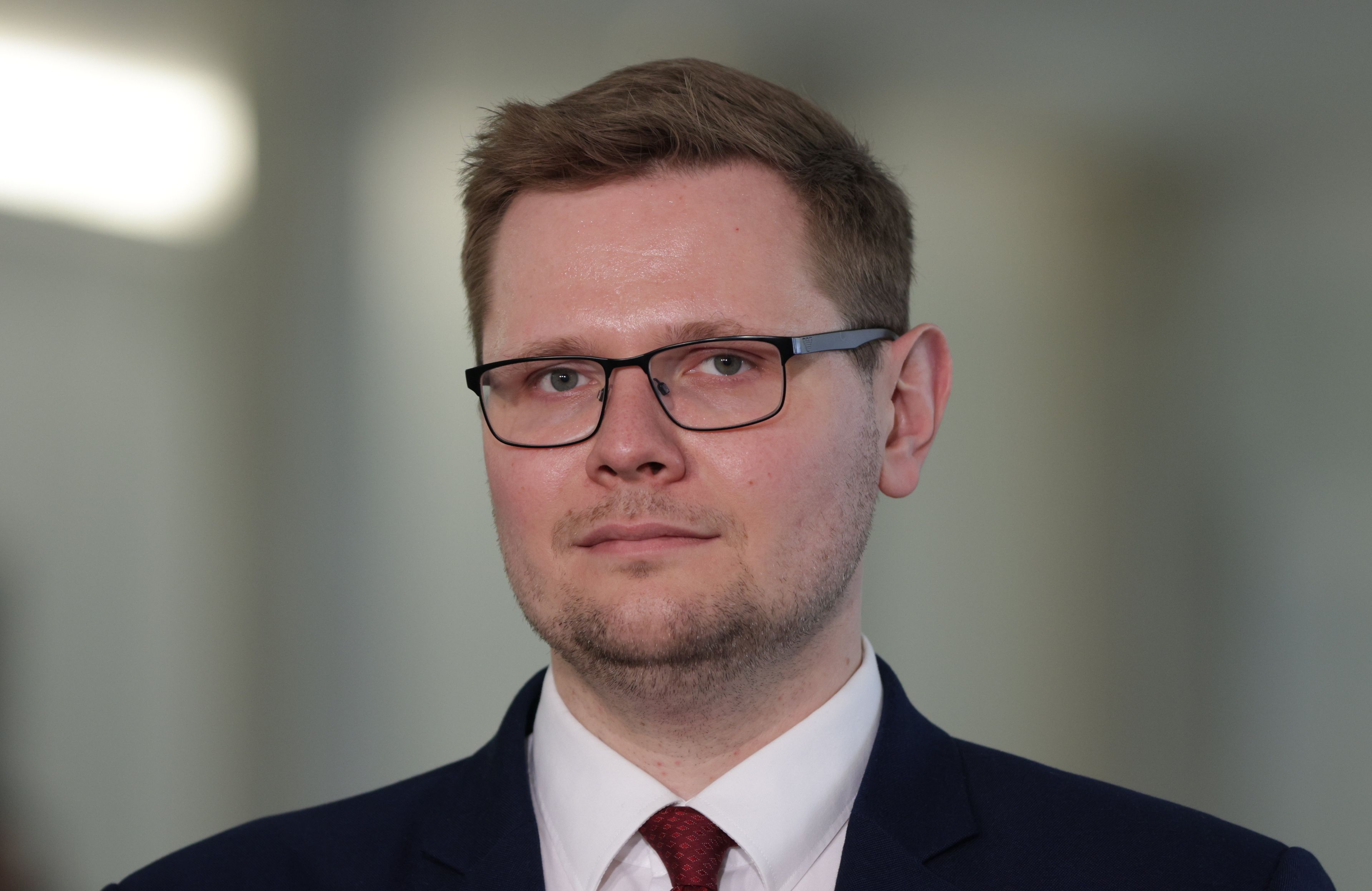 Mężczyzna w garniturze, w prostokątnych okularach i blond włosach - zdjęcie portretowe