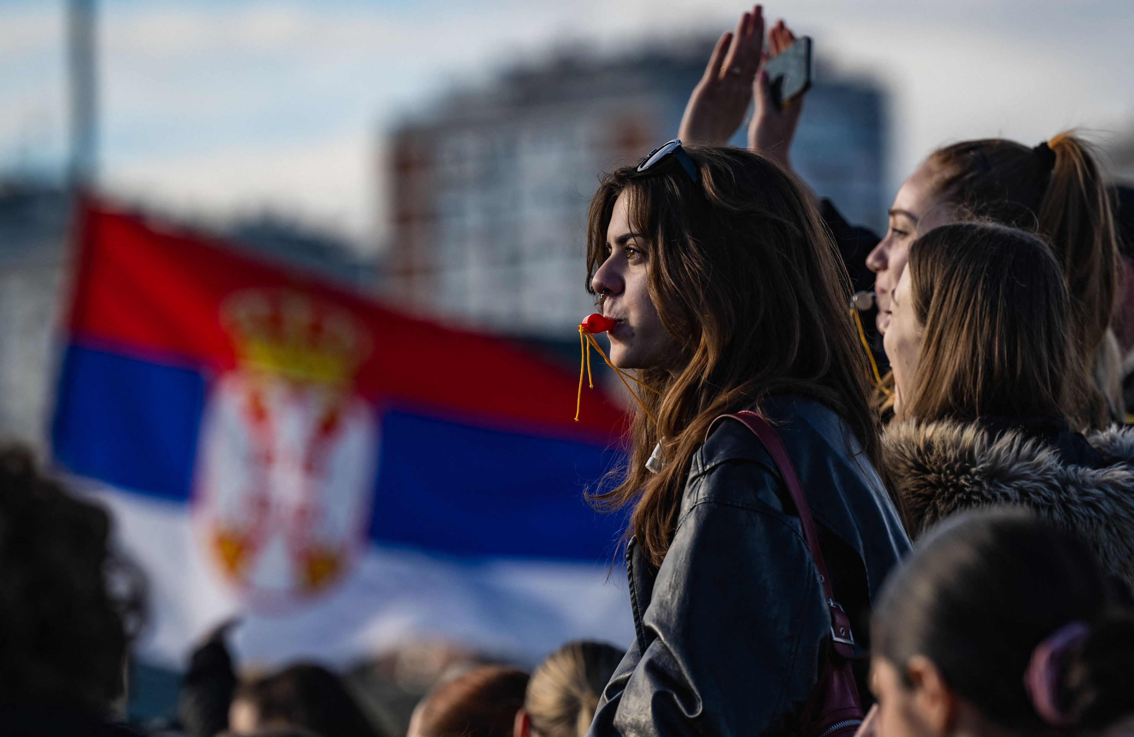 Młoda kobieta z profilu na tle czerwono-niebiesko-białej flagi.