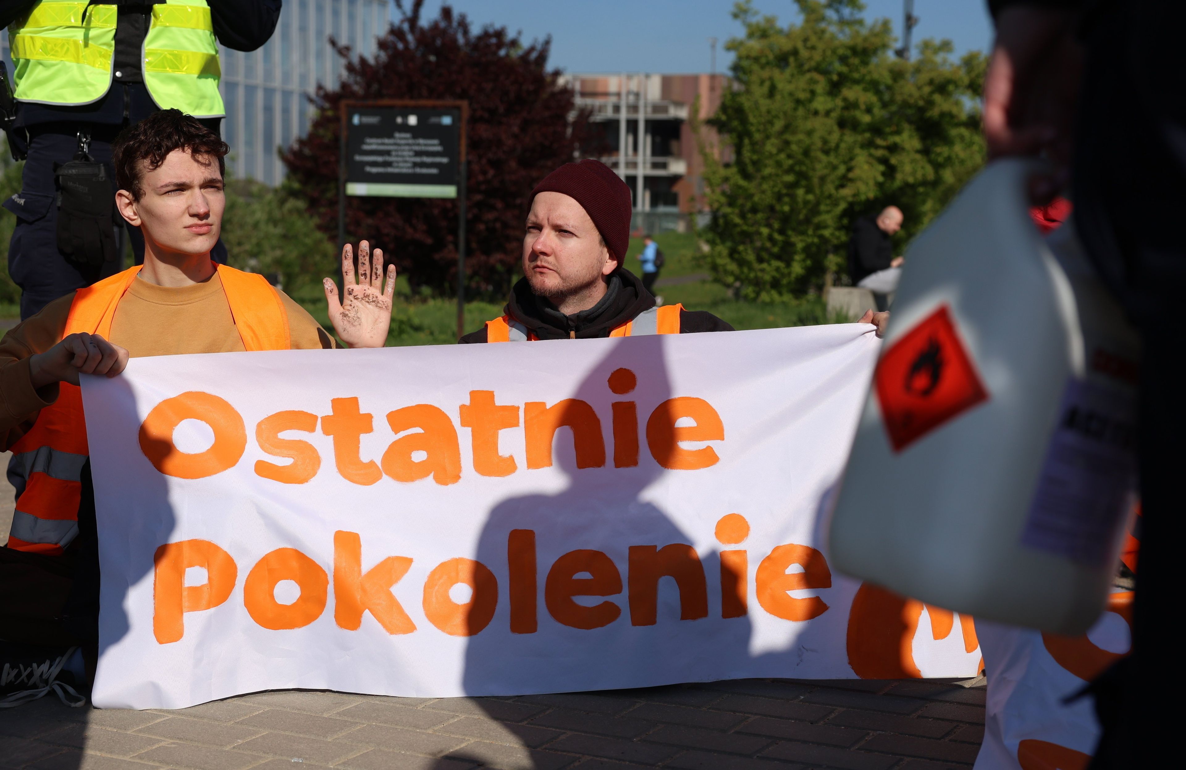 dwoje młodych ludzi blokuje drogę i trzyma napis ostatnie pokolenie