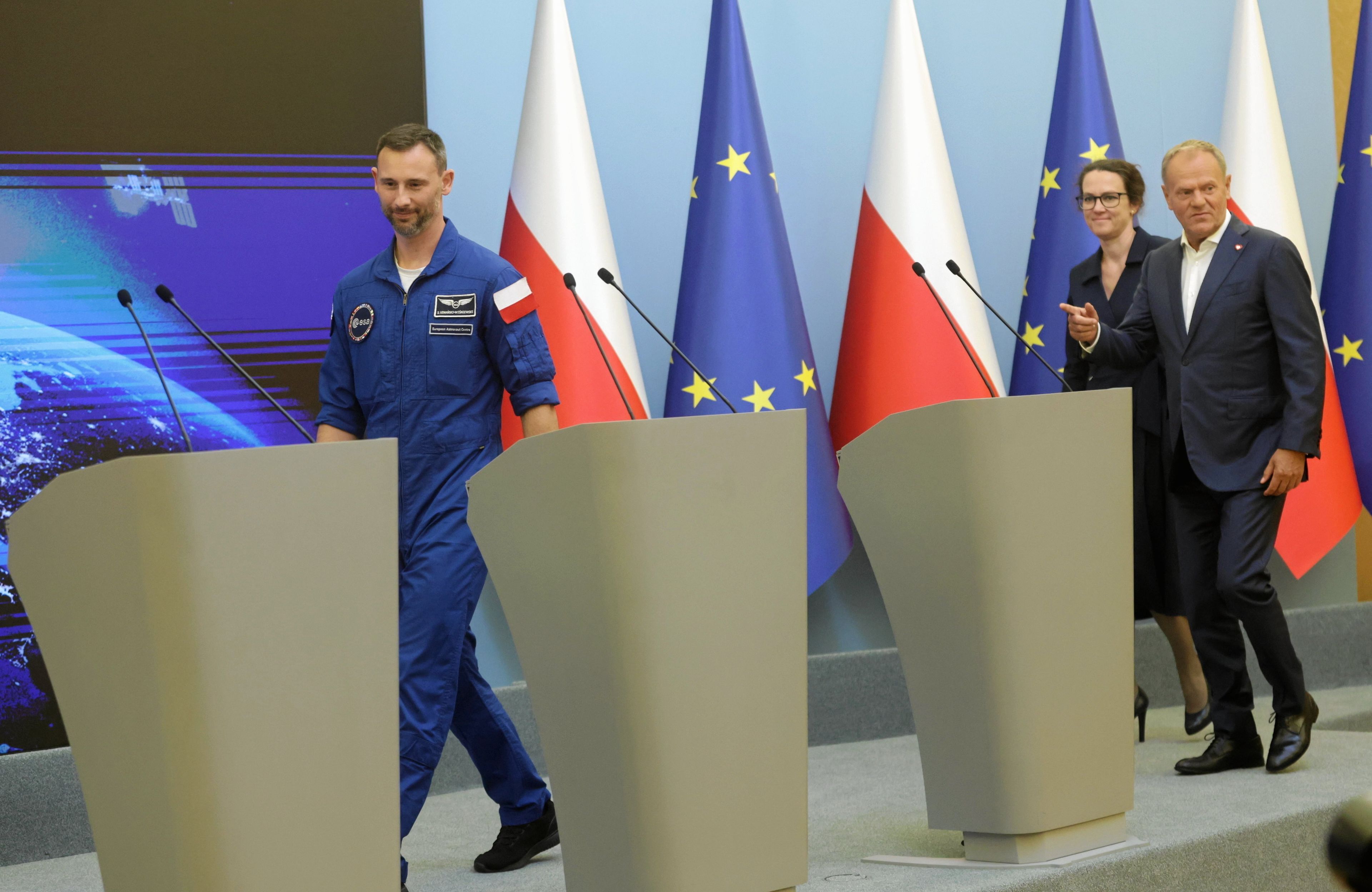 Sławosz Uznański-Wiśniewski, Donald Tusk i Marta Wachowicz (szefowa POLSA) wchodzą do sali, gdzie odbywała się konferencja prasowa po lądowaniu misji Ignis, 24.07.2025 r.
