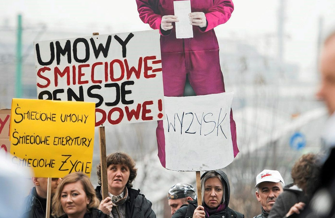 Demonstracja pracowników przeciw tzw. umowom śmieciowym. Trzymają transparenty o teście "umowy śmieciowe, pensje głodowe" oraz "wyzysk"