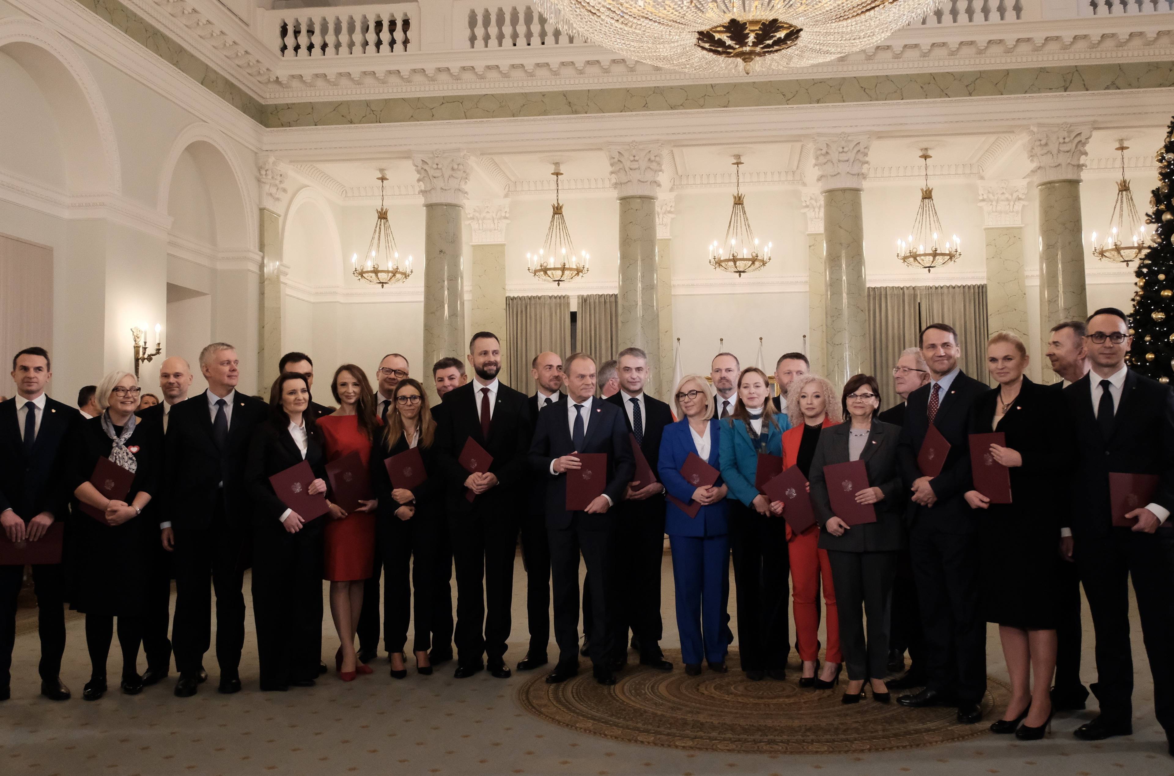 Rząd Tuska: grupowe zdjęcie kobiet i męzczyzn pod zyrandolem w pałacu prezydenckim