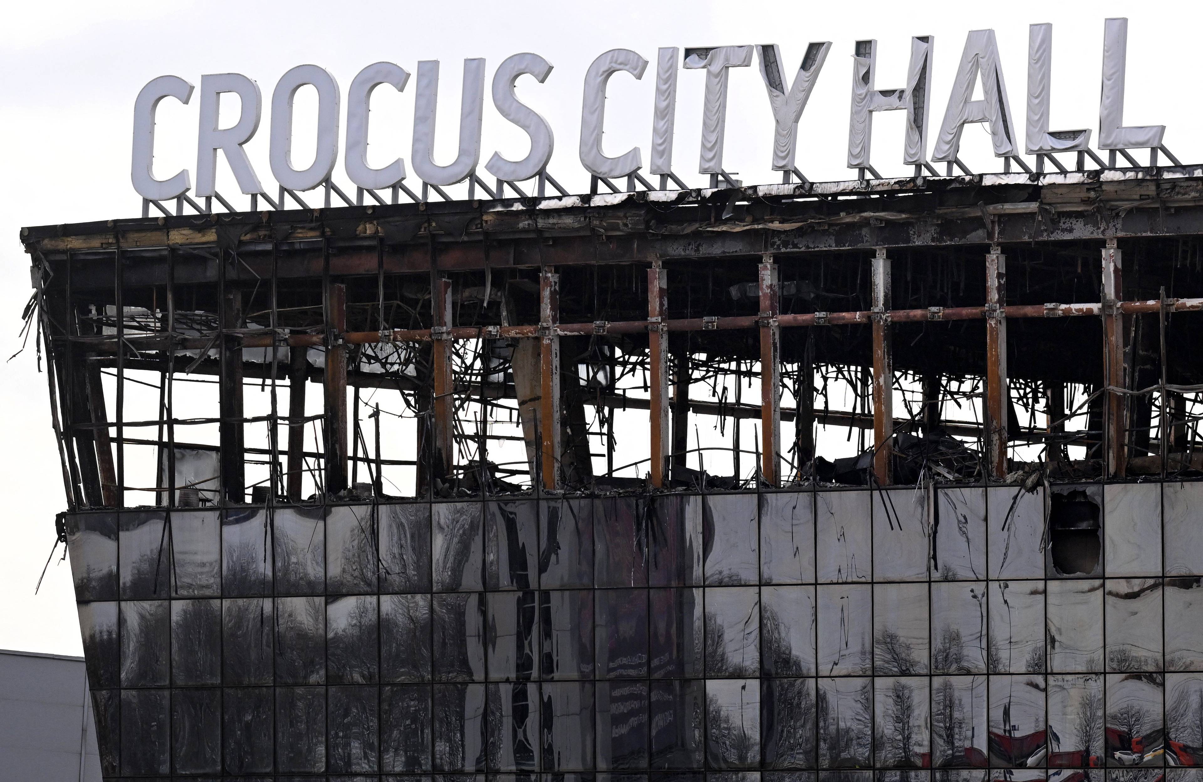 wypalony szkielet budynku z szyldem na dachu: Crocus City Hall