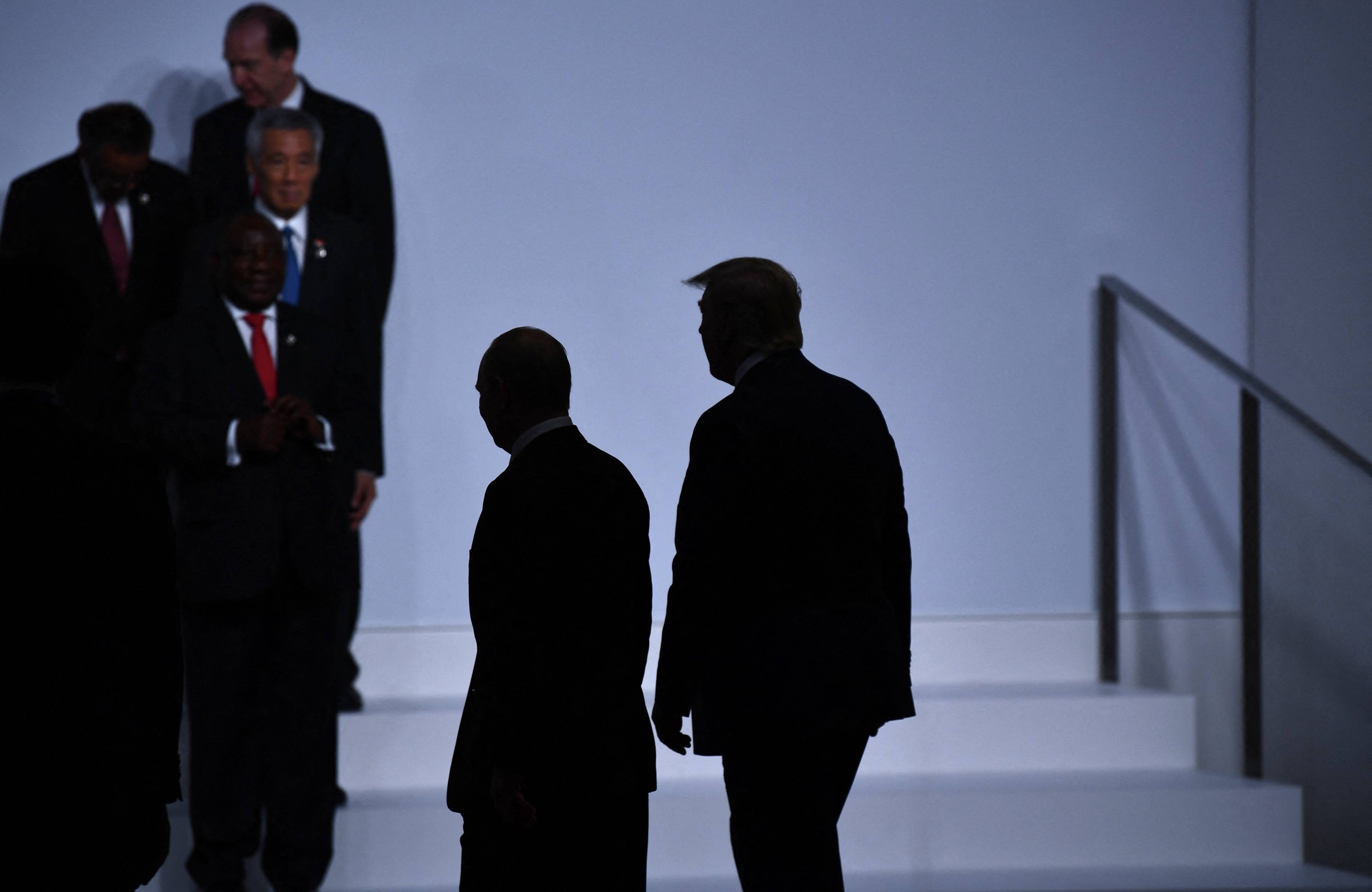 Władimir Putin i Donald Trump idą obok siebie, pada na nich cień
