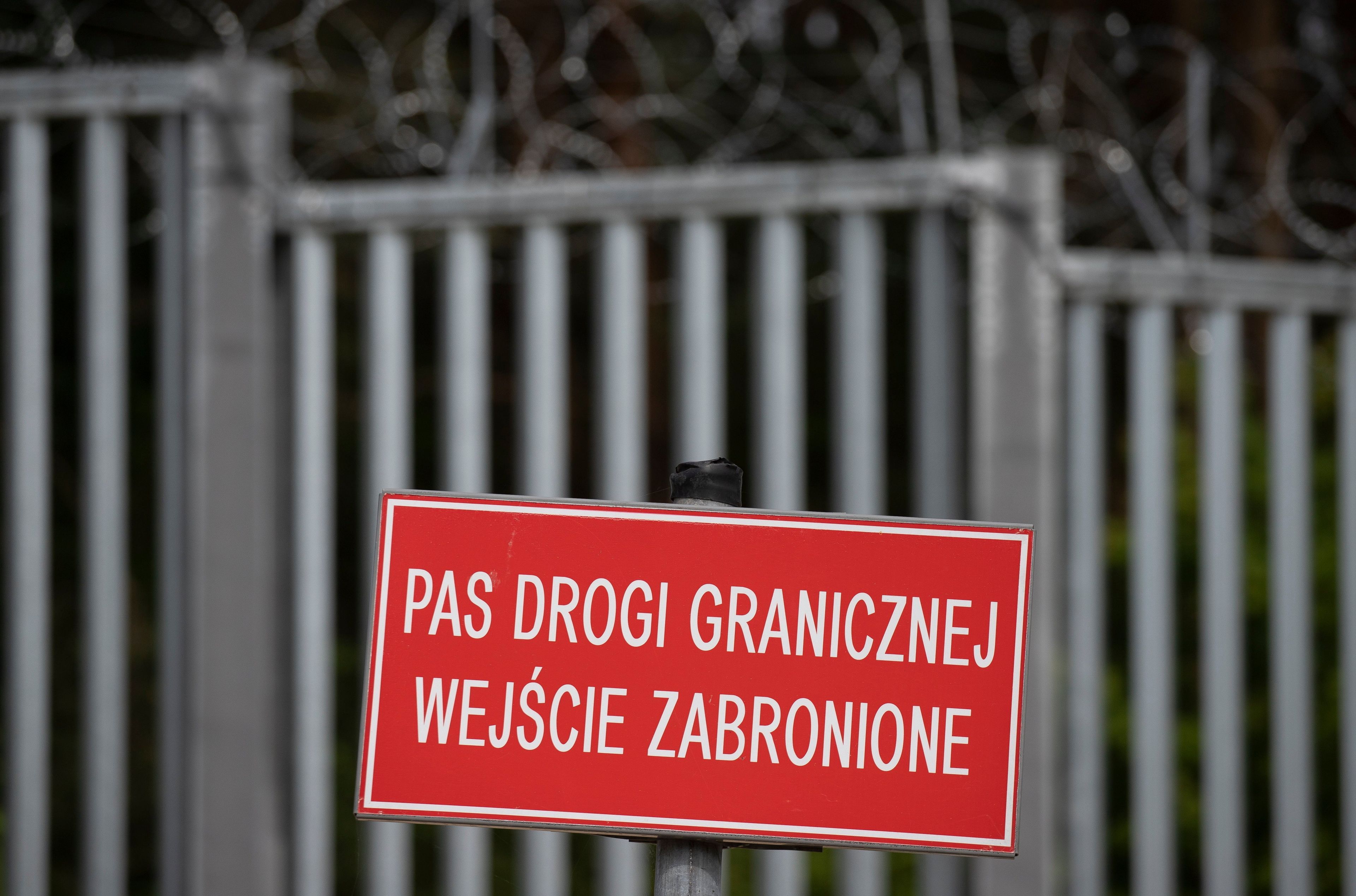 Płot na granicy polsko-białoruskiej. Na pierwszym planie tablica z napisem "Pas drogi granicznej wejście zabronione:
