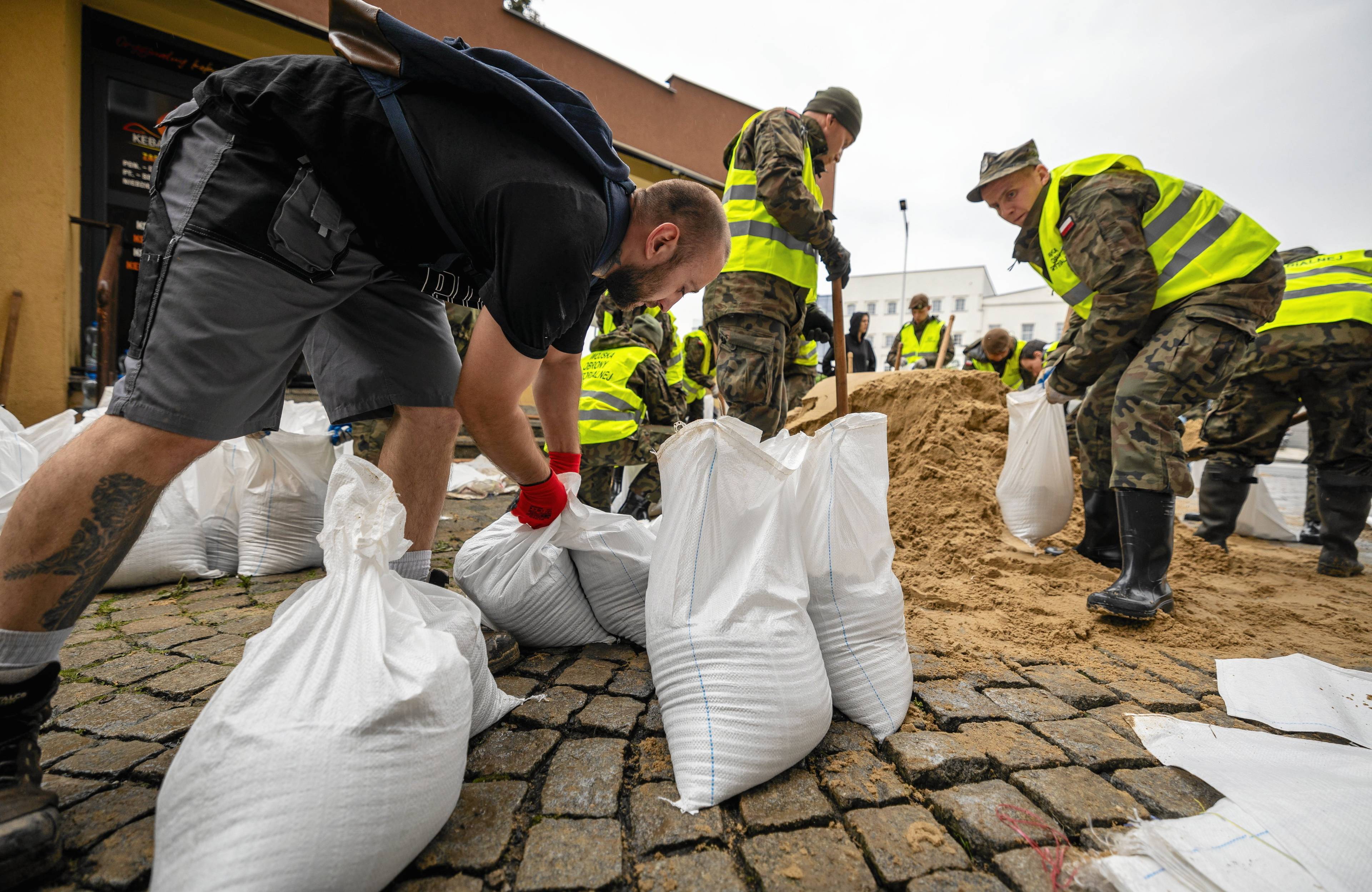 Ludzie układają worki z piaskiem zabezpieczające przed powodzią