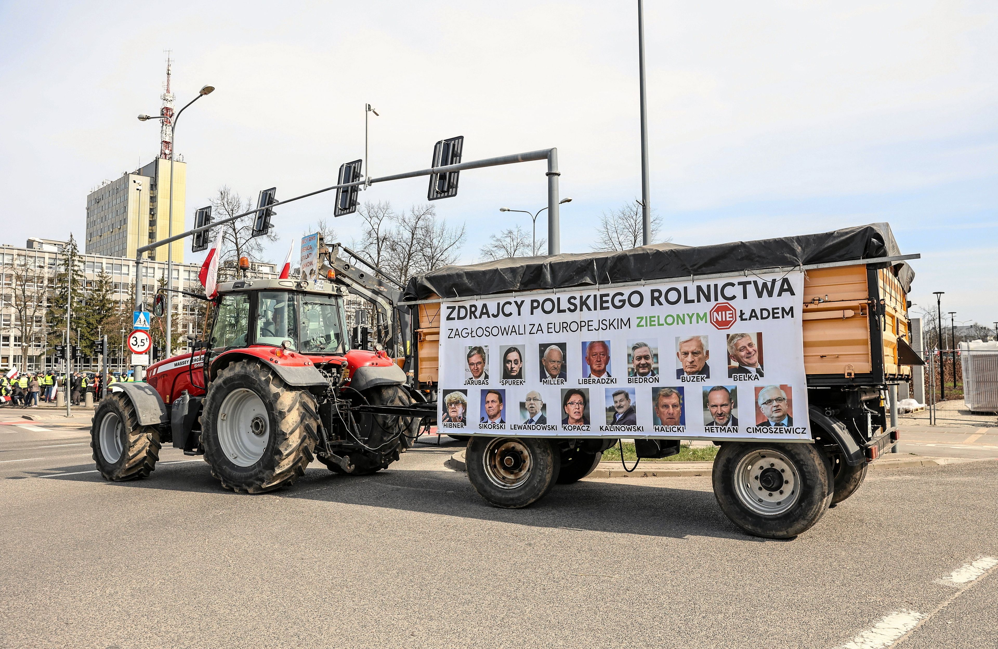 Traktor na ulicach Kielc. Na przyczepie napis: Zdrajcy polskiego rolnictwa. Głosowali za Zielonym Nie Ładem. Poniżej portrety kilkunastu europosłów