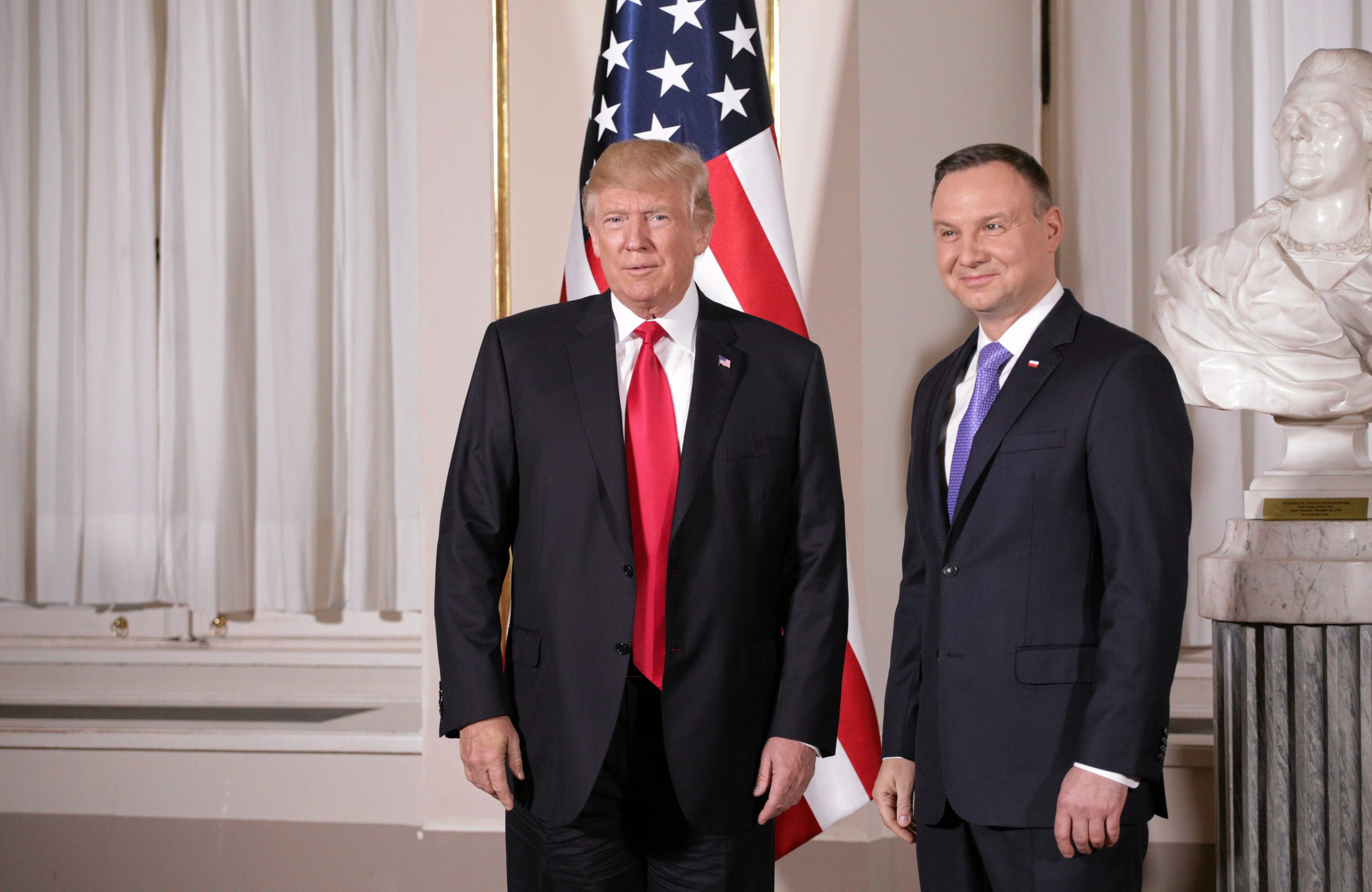 Andrzej Duda i Donald Trump stoją obok siebie, w tle amerykańska flaga