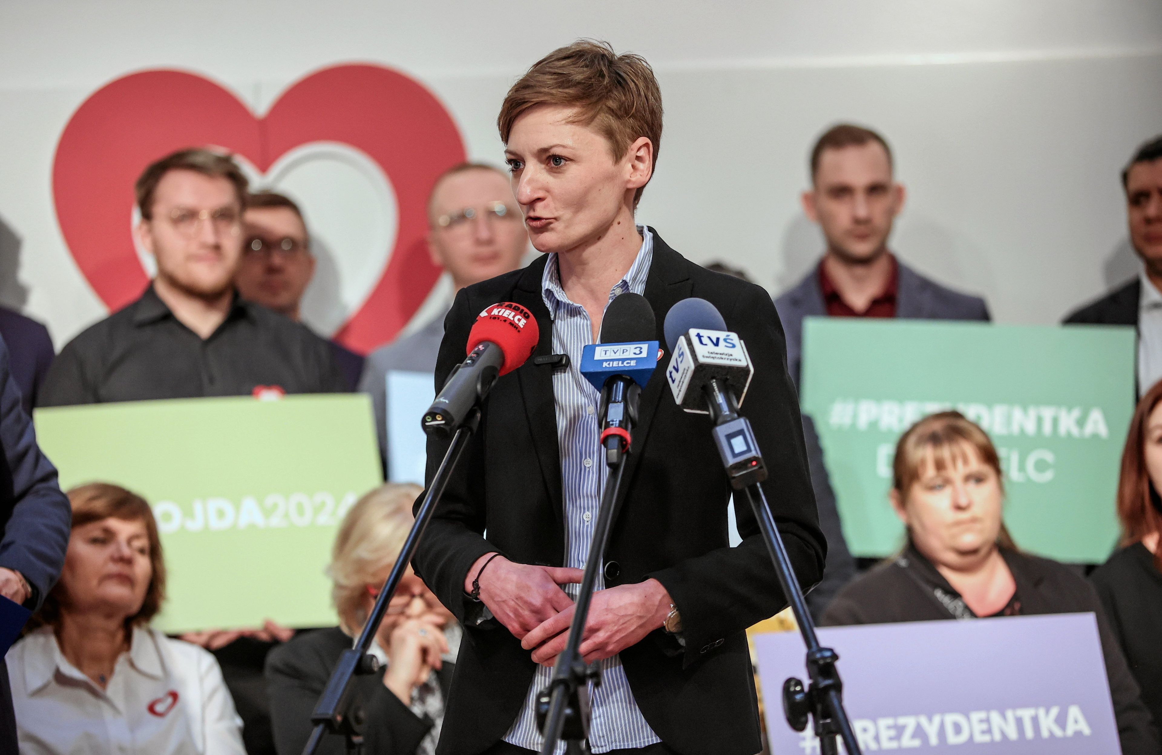 Agata Wojda przy mikrofonie na tle działaczy