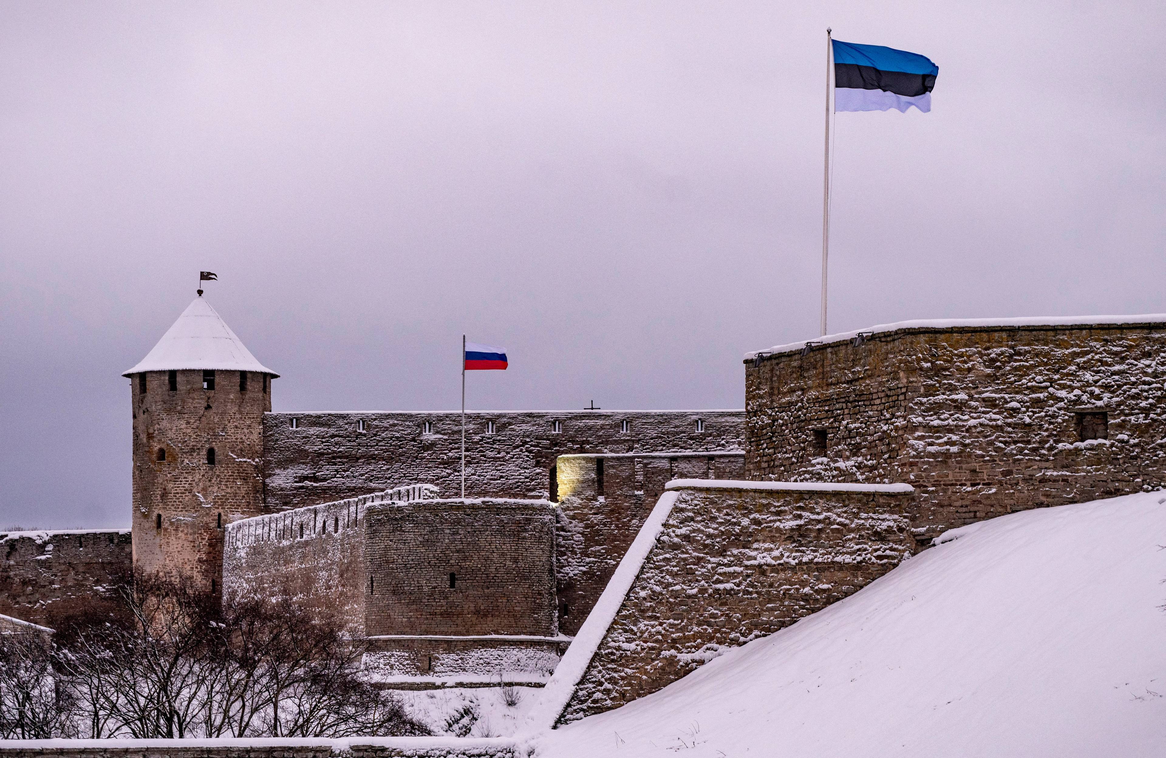 Ośnieżony zamek w Narwie na granicy rosyjsko-estońskiej, w dali powiewa flaga rosyjska, bliżej widać estońską