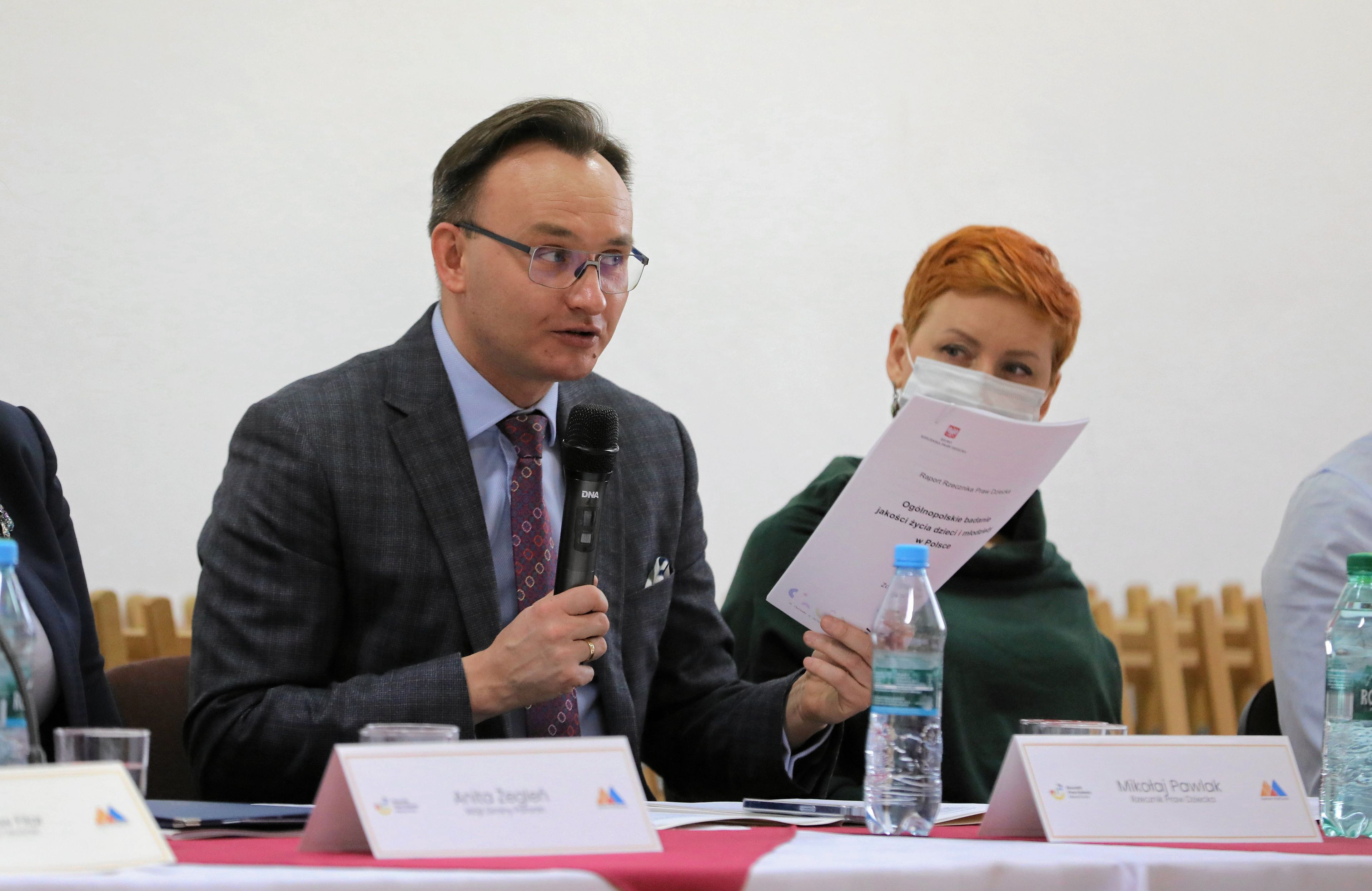 Mikołaj Pawlak przemawia, siedząc za stołem