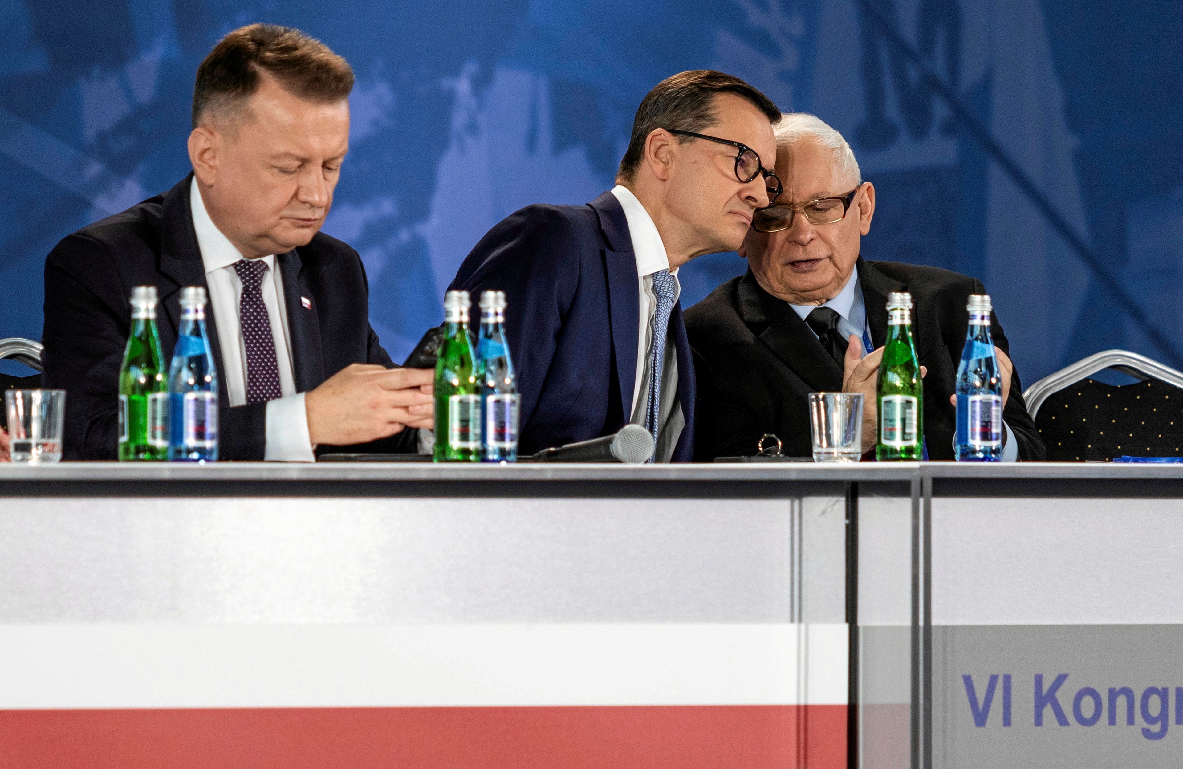 Trzech mężczyzn za stołem prezydialnym
