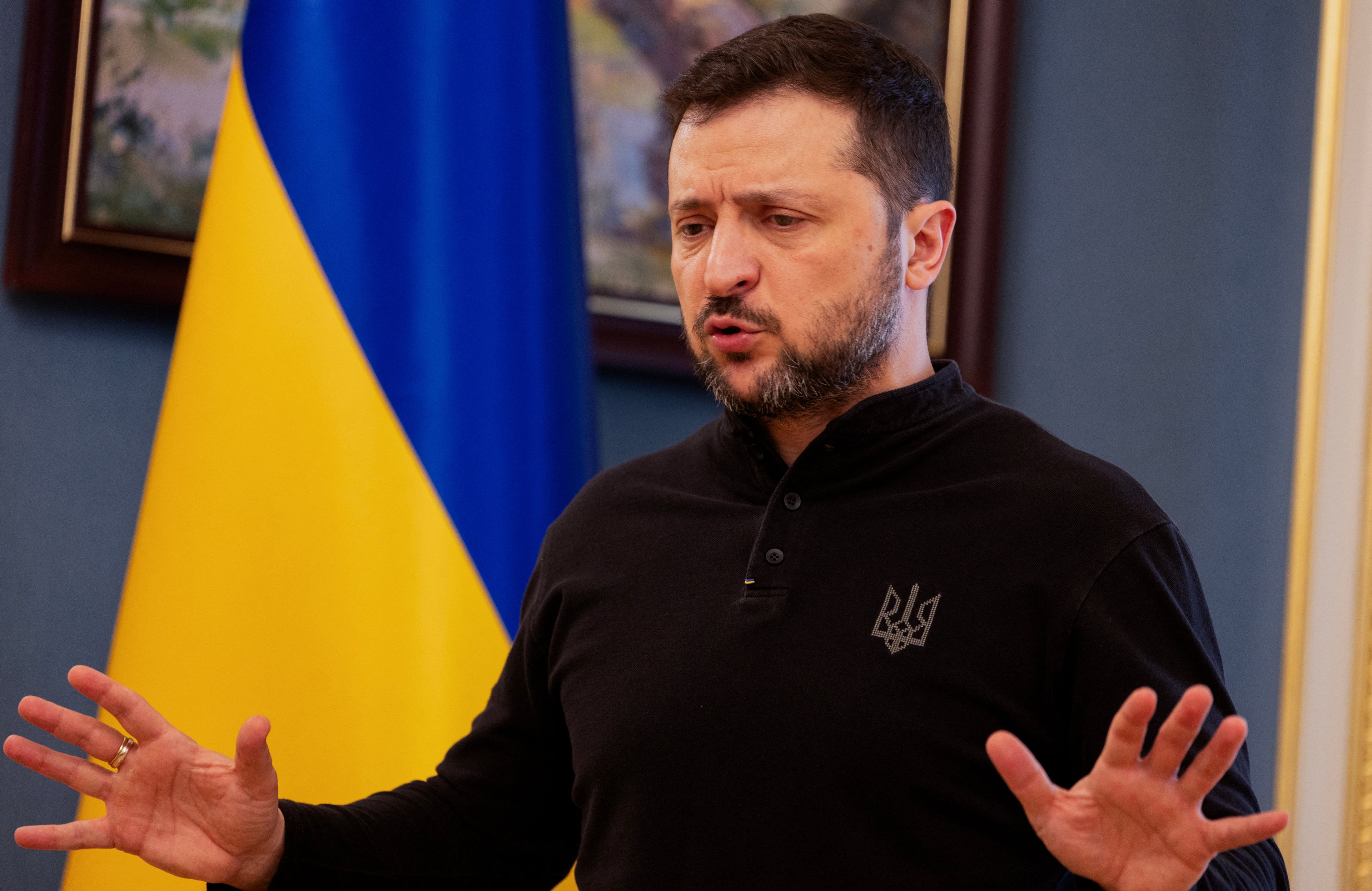 Mężczyzna stoi i przemawiając rozkłada ręce