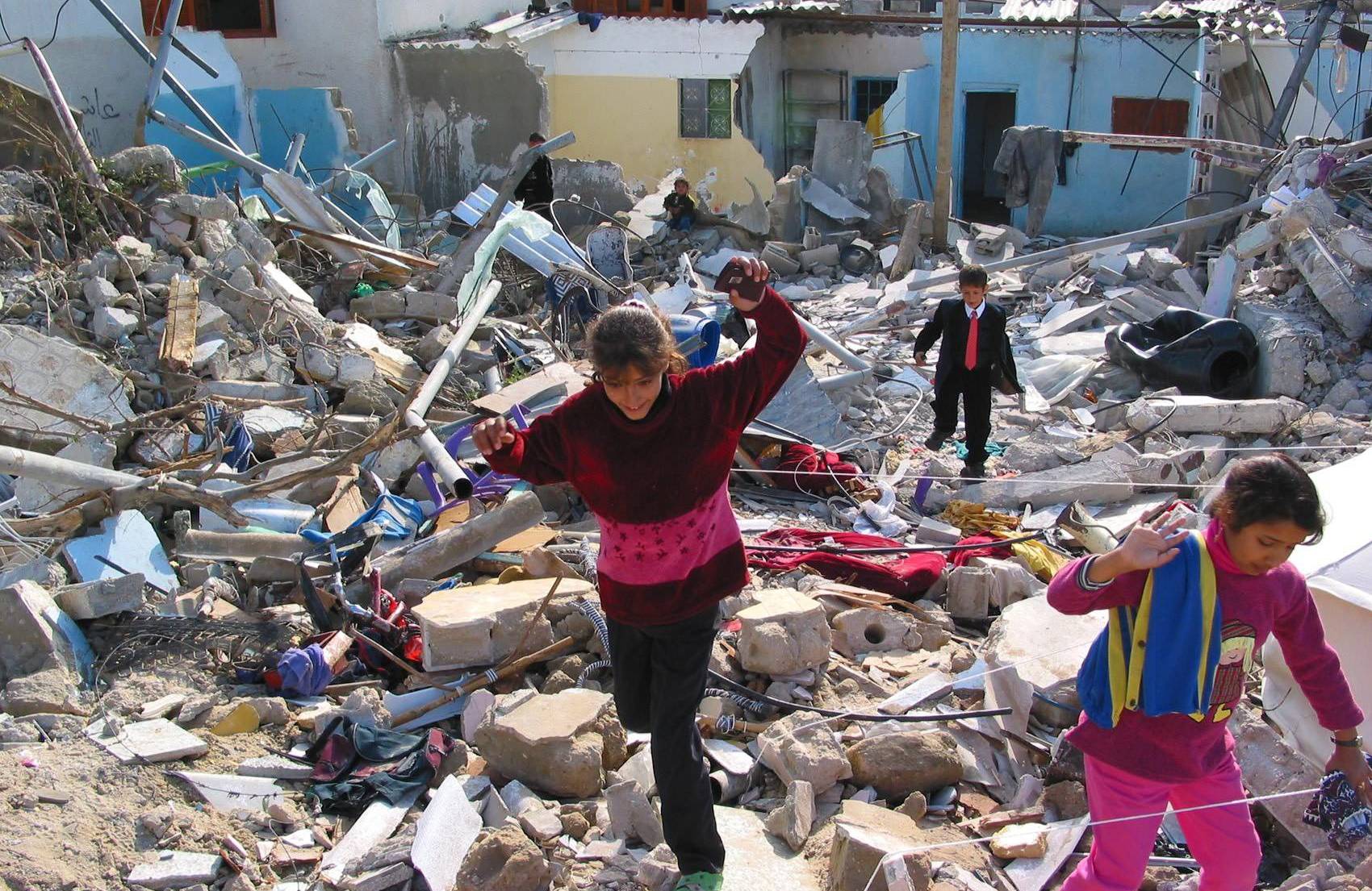 Dzieci uciekają po gruzach budynków