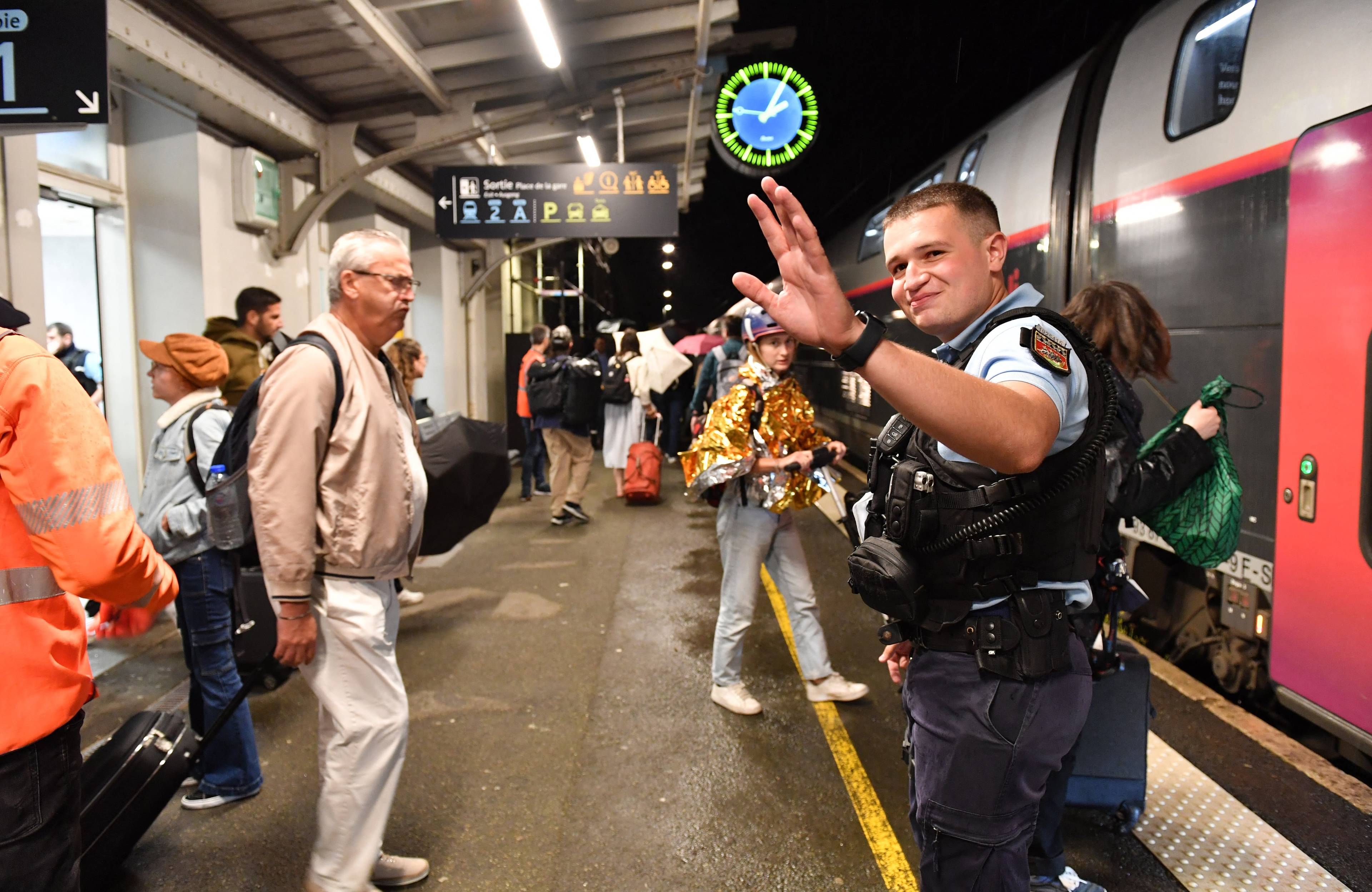 policjant i podróżni na peronie dworca TGV