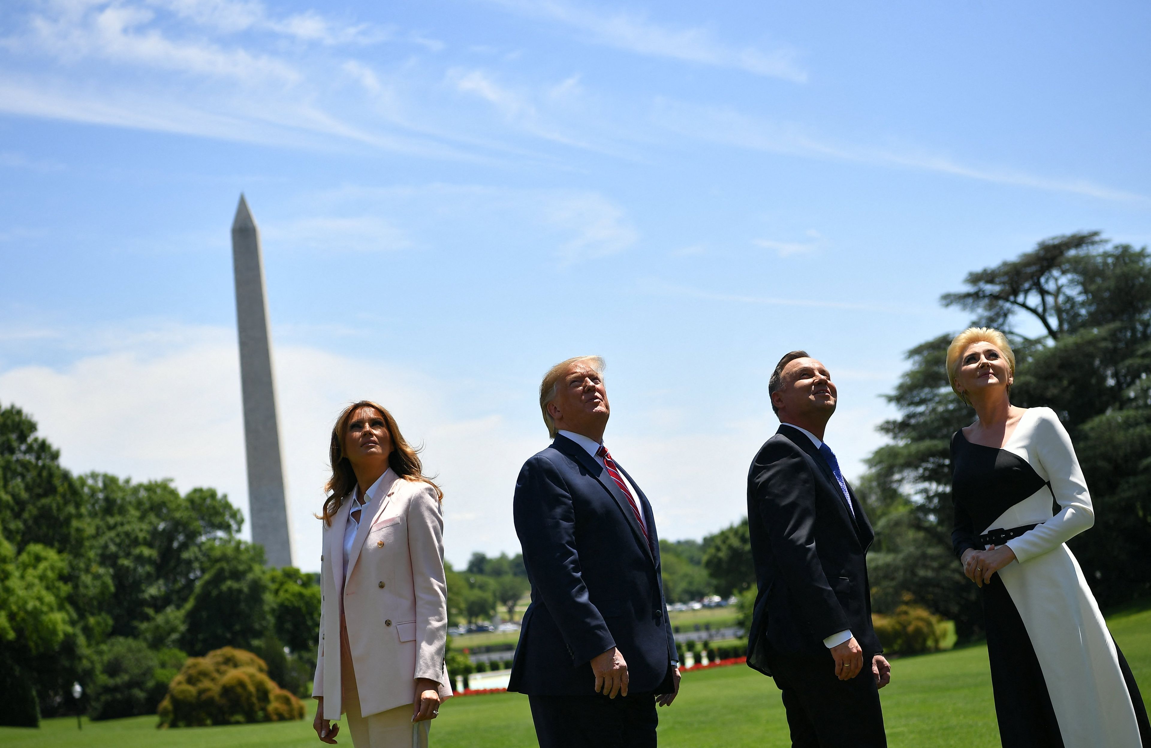 Dwie kobiety i dwóch mężczyzn patrzący w niebo, w tle obelisk