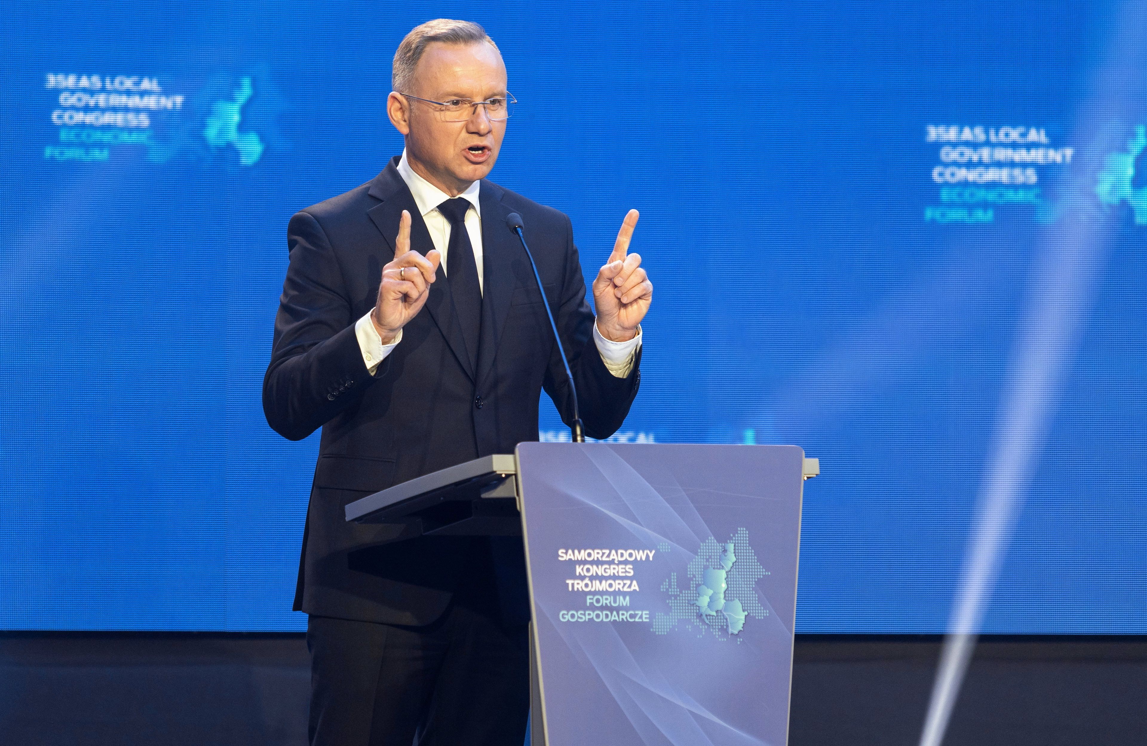 Mężczyzna przemawia unosząc w górę ręce