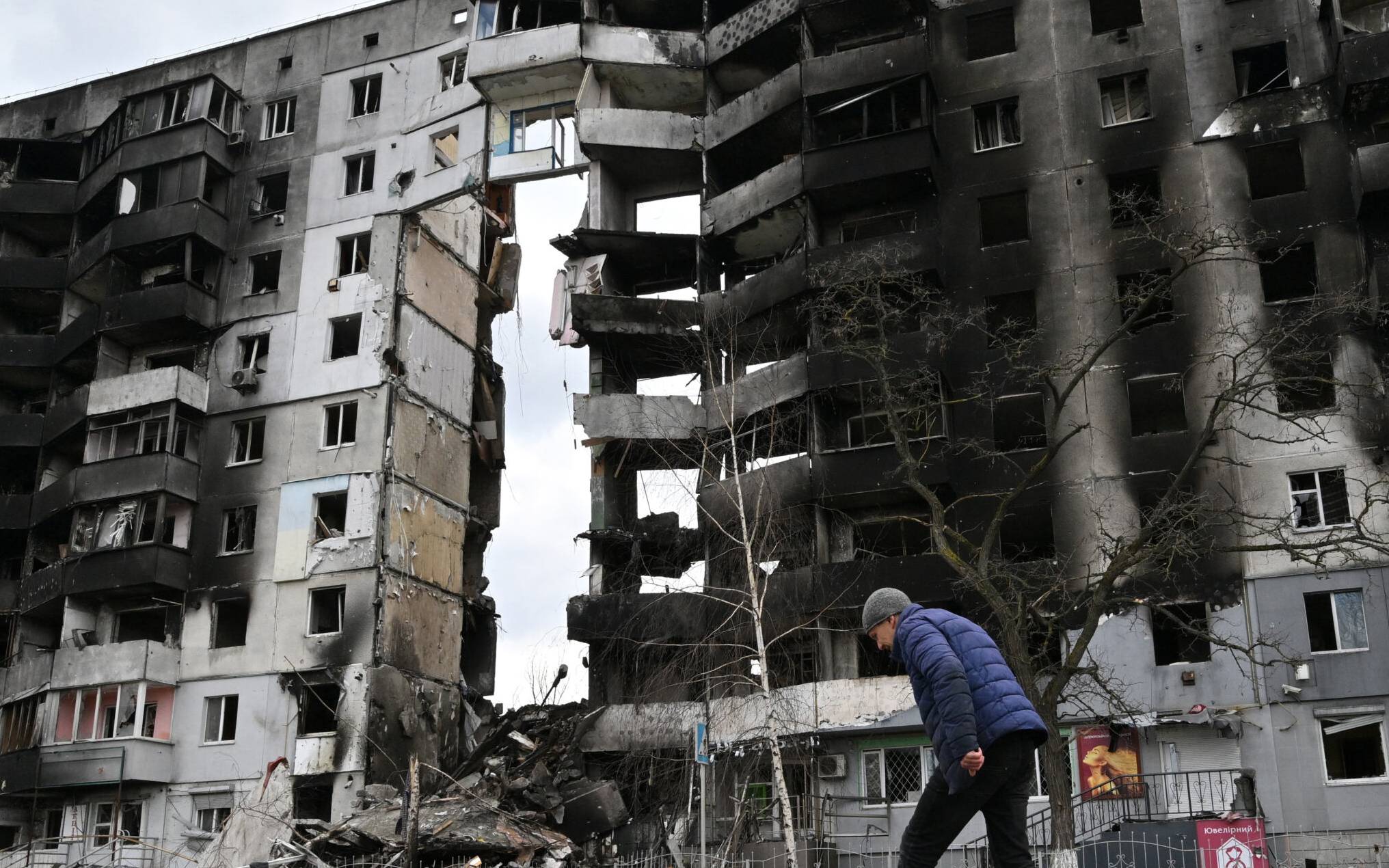 A man walks past destroyed buildings in the town of Borodianka, northwest of Kyiv on April 4, 2022. - The EU said on April 4, 2022, it is urgently discussing a new round of sanctions on Russia as it condemned "atrocities" reported in Ukrainian towns that have been occupied by Moscow's troops. Russia invaded Ukraine on February 24, 2022. (Photo by Sergei SUPINSKY / AFP)