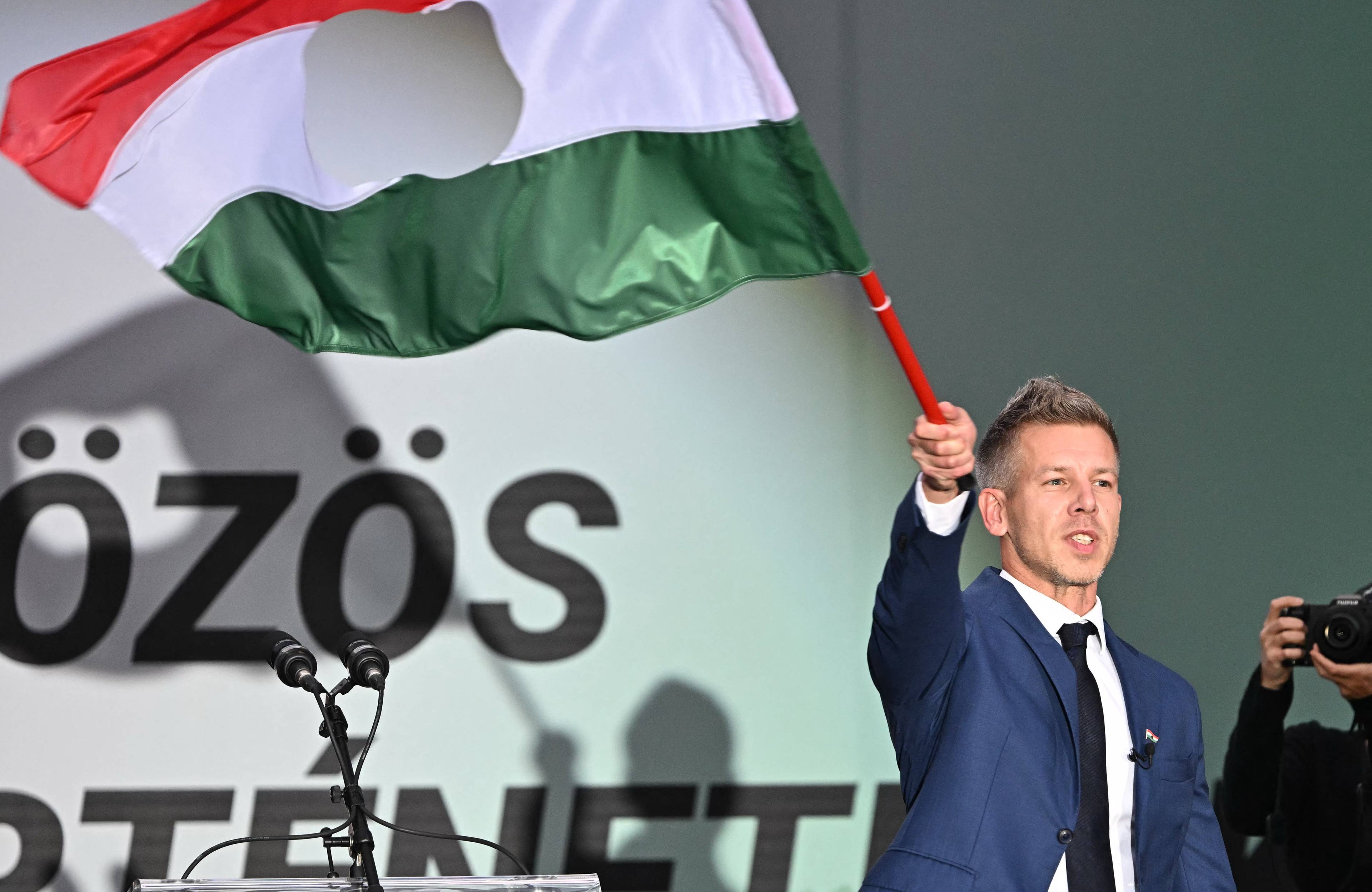 40-latek w garniturze wymachujący wielką czerwono-biało-zieloną flagą