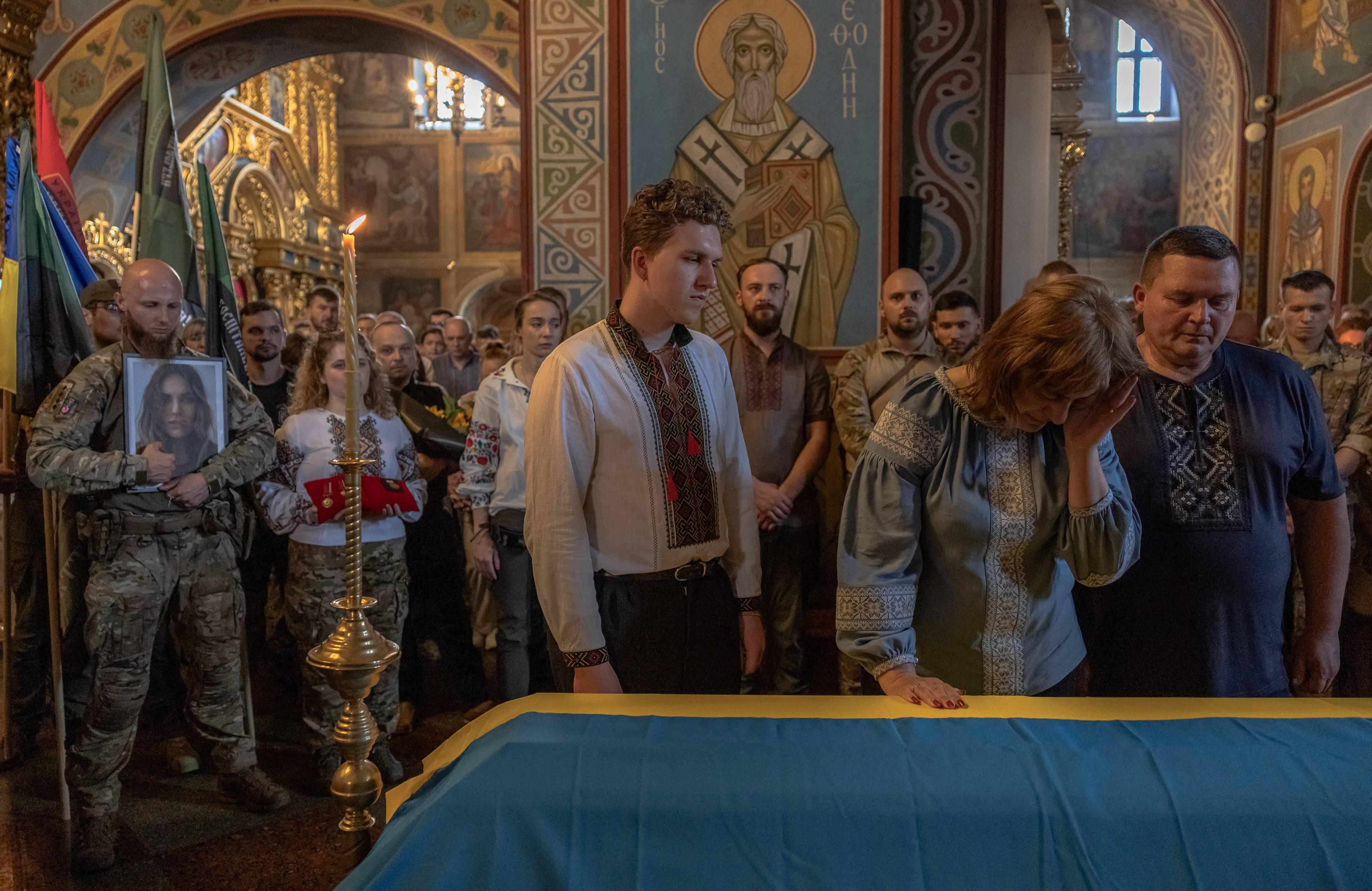 Na zdjęciu w cerkwi obok trumny przykrytej flagą żółto-niebieską stoi rodzina Iryny Cybuch: brat Jurij z matką oraz ojcem. Są w koszulach wyszywanych. W tle są inni ludzie