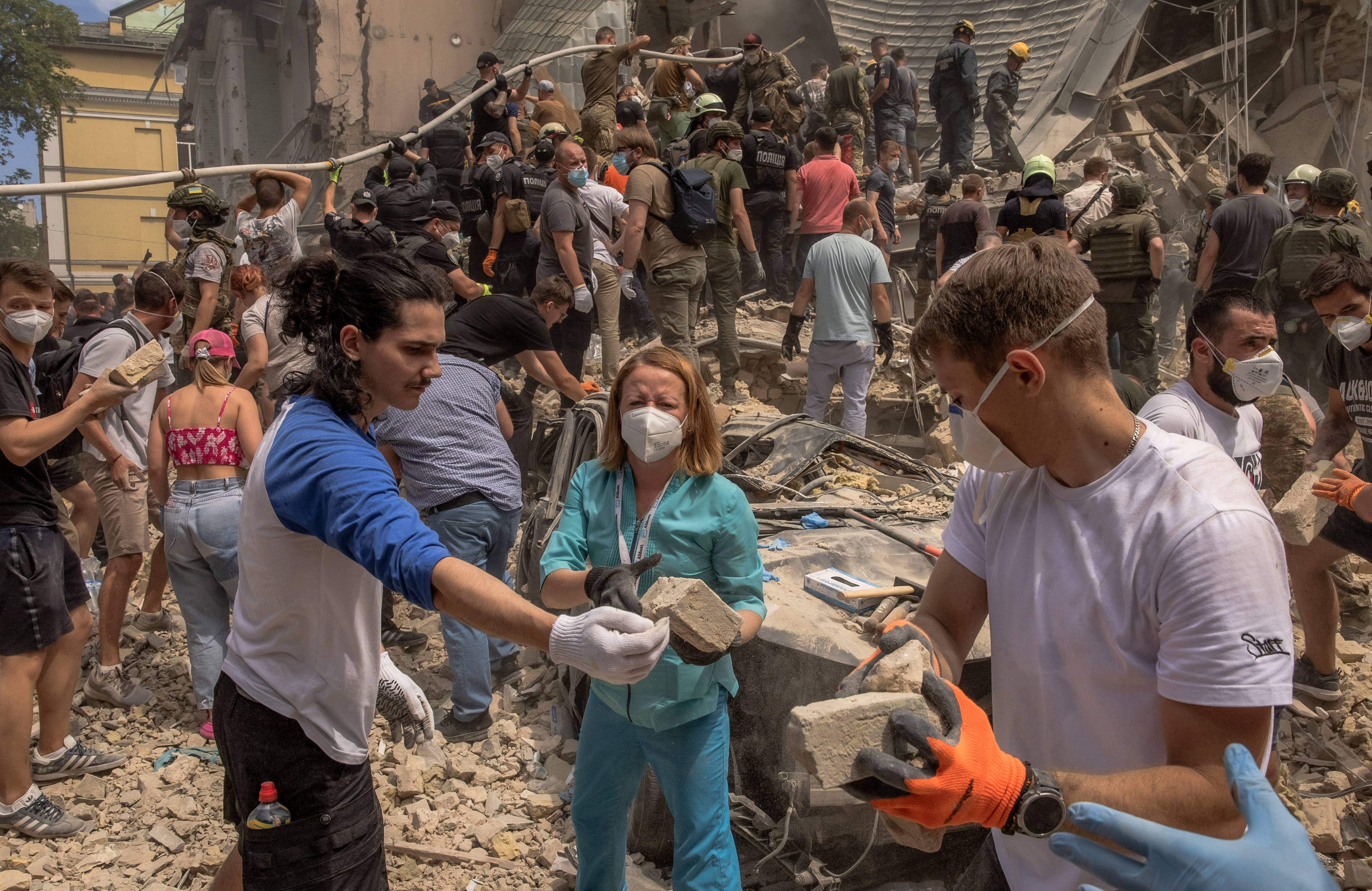 Na zdjęciu są ludzie wśród gruzów szpitala dziecięcego. Pomagają ratownikom w akcjo poszukiwawczej