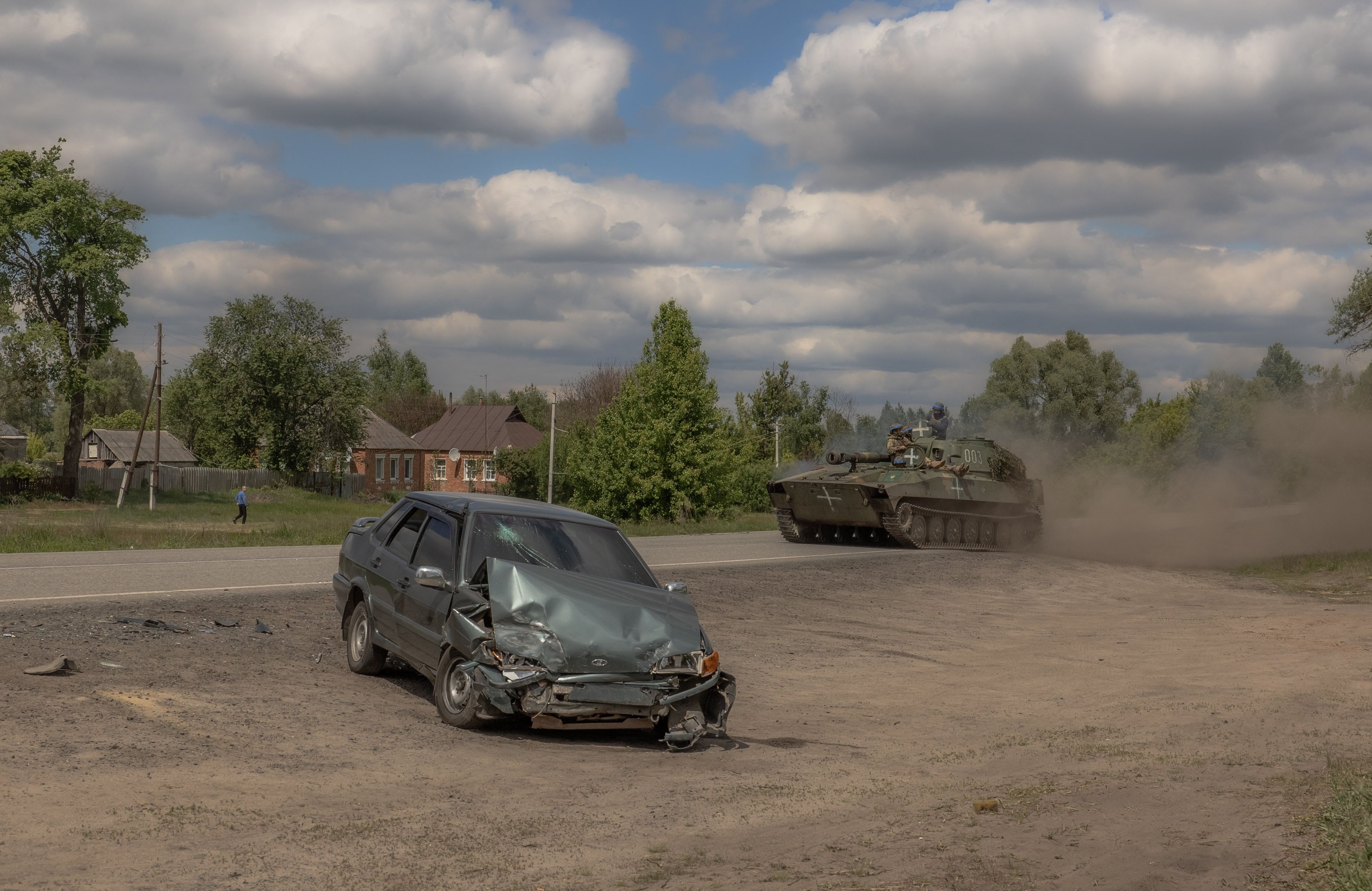 ostrzelany samochód na pustym placu, za nim jedzie haubica