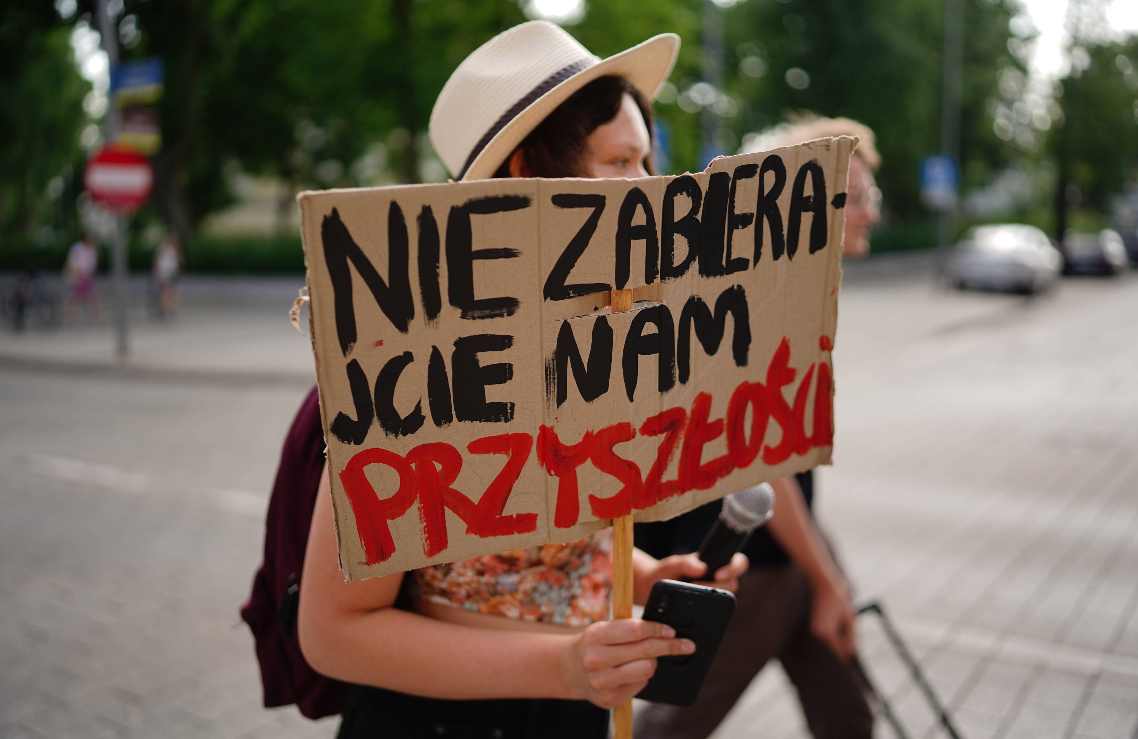 Młoda kobieta z plakatem, na którym napisała "Nie zabierajcie nam przyszłości"