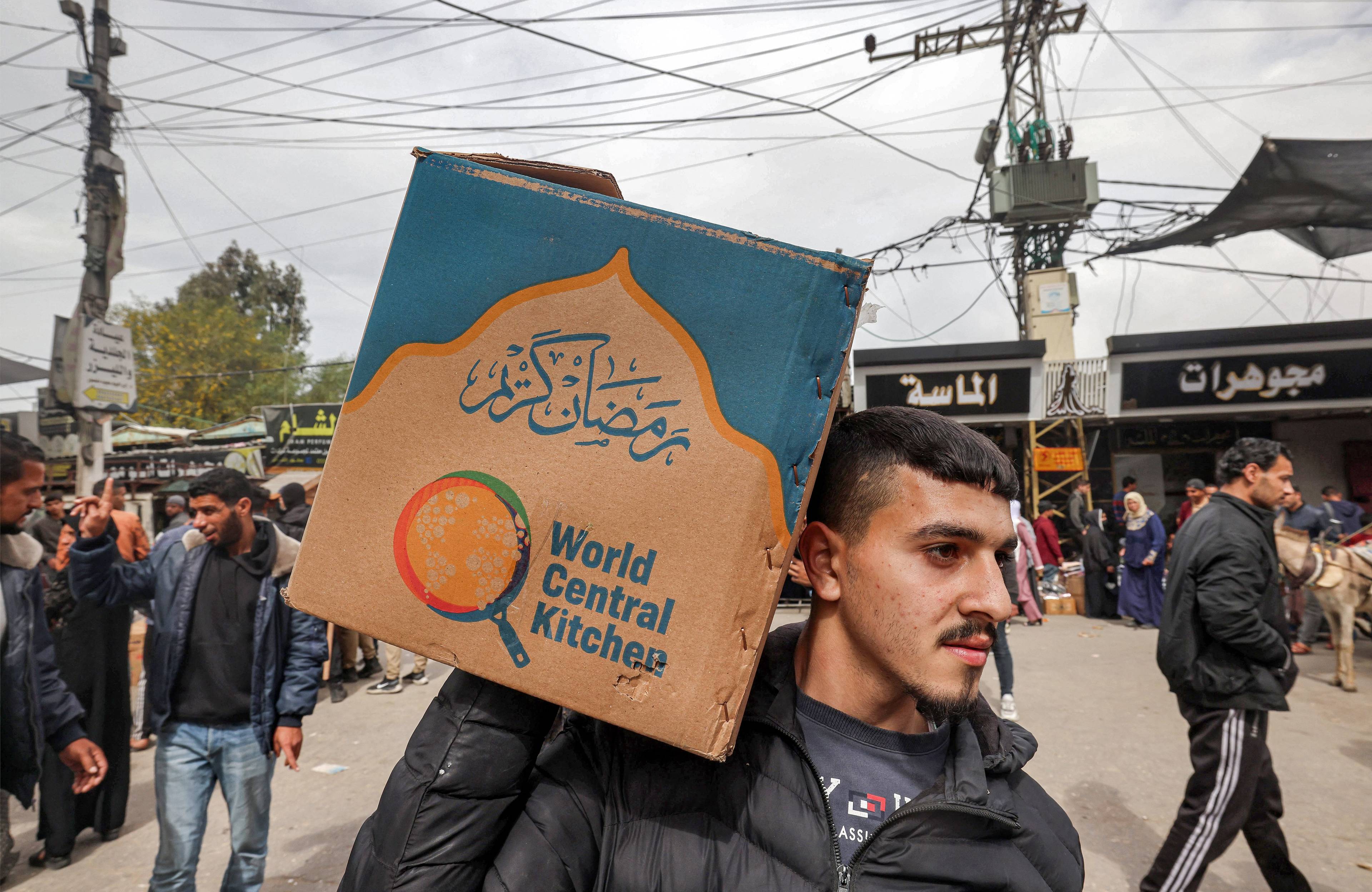 Palestyński mężczyzna trzyma na ramieniu pudło z napisem "World Central Kitchen"