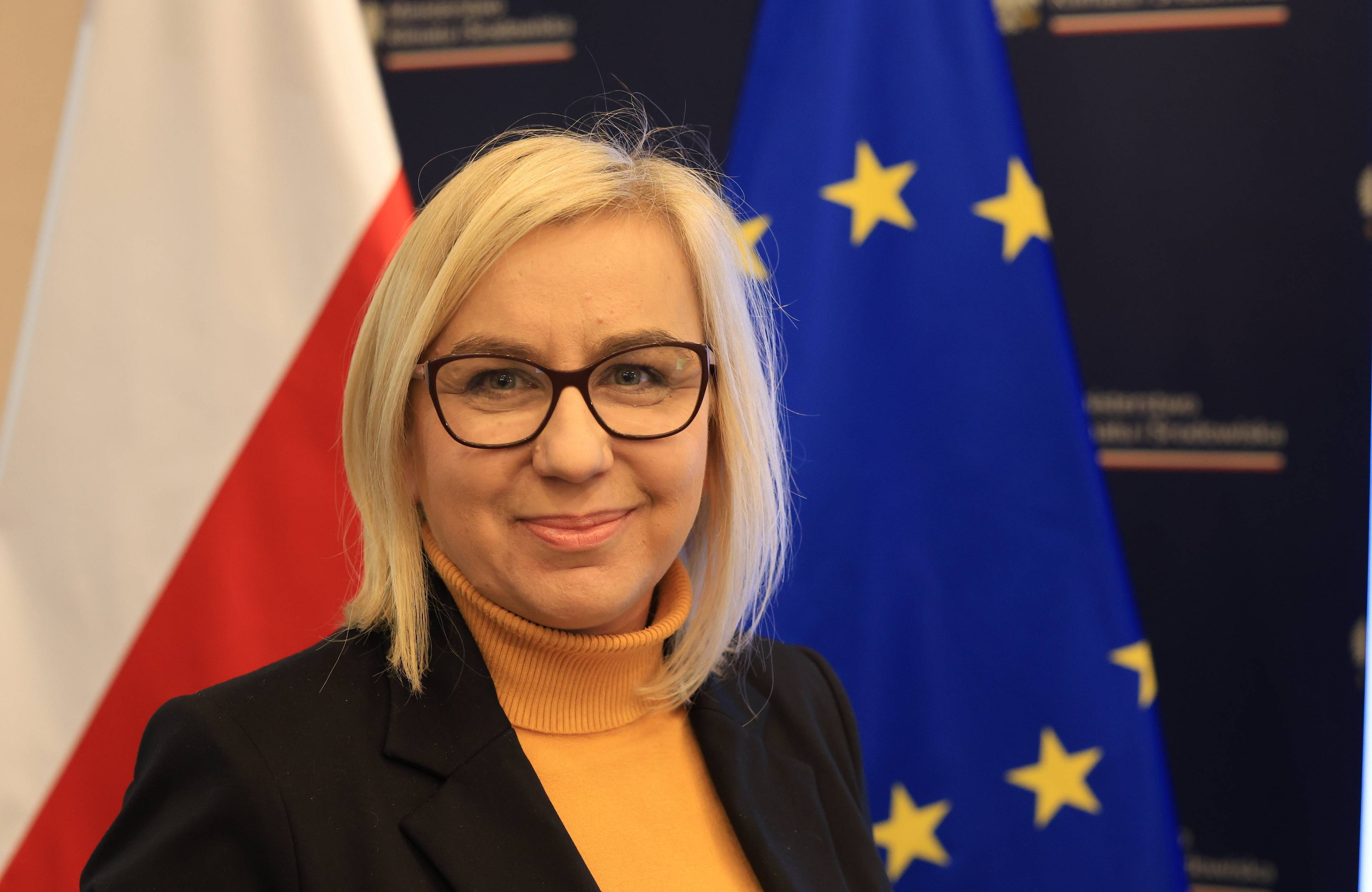 Ministra Paulina Henning-Kloska na tle flag Polski i Unii Europejskiej