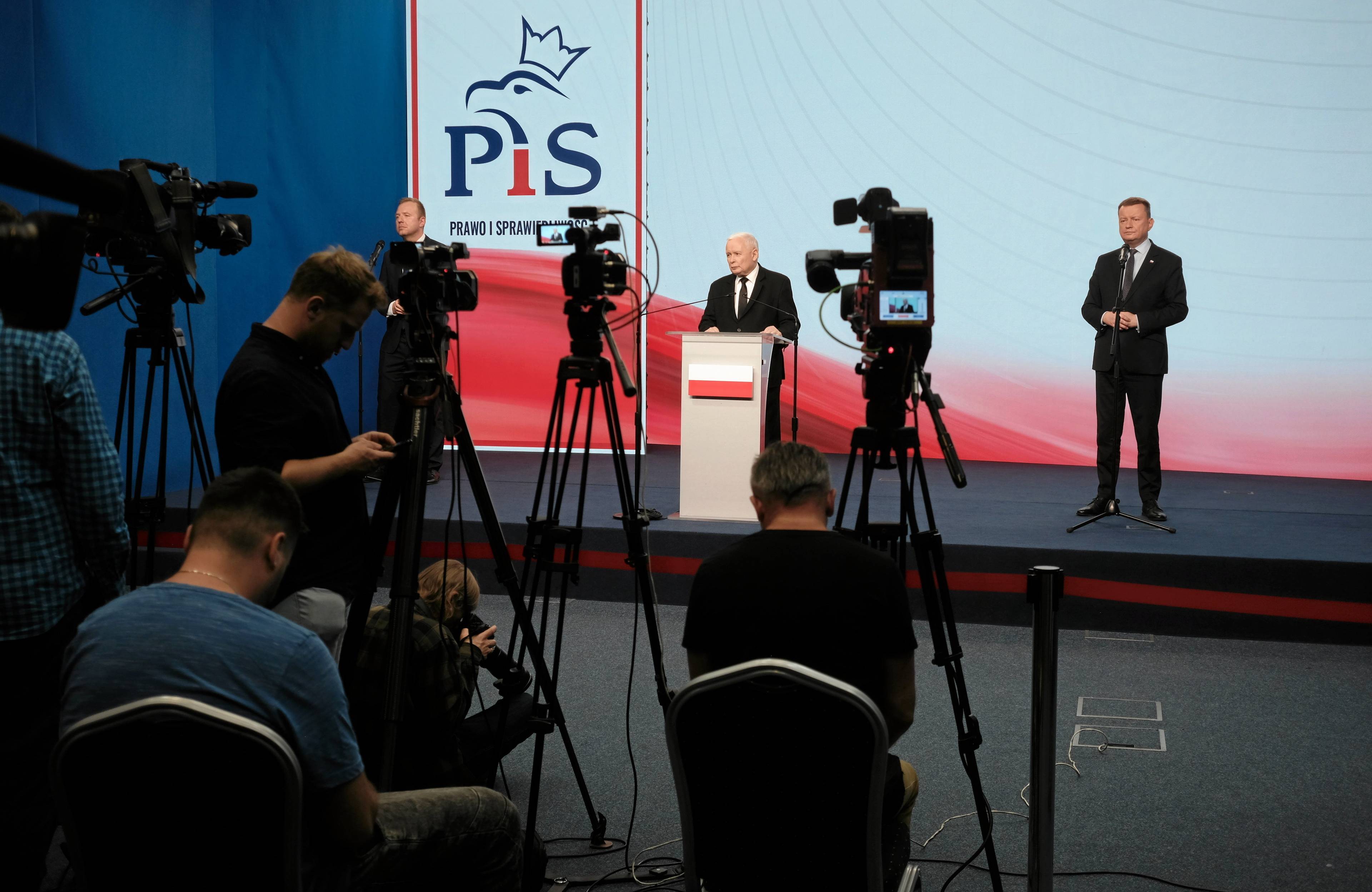 Jarosław Kaczyński i Mariusz Błaszczak filmowani przez kamery na konferencji prasowej