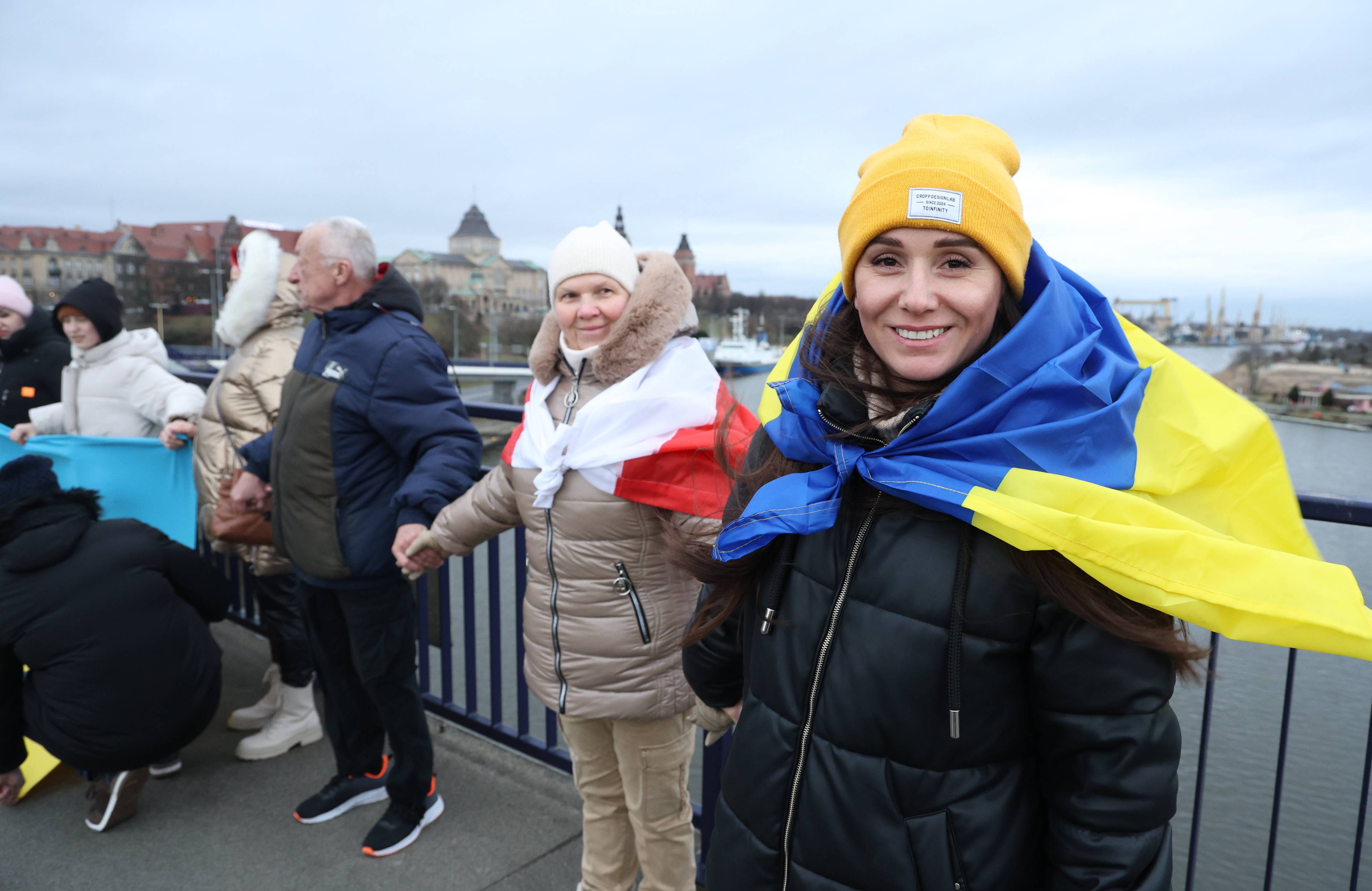 Ludzie owinięci we flagi Ukrainy i Polski trzymają się za ręce